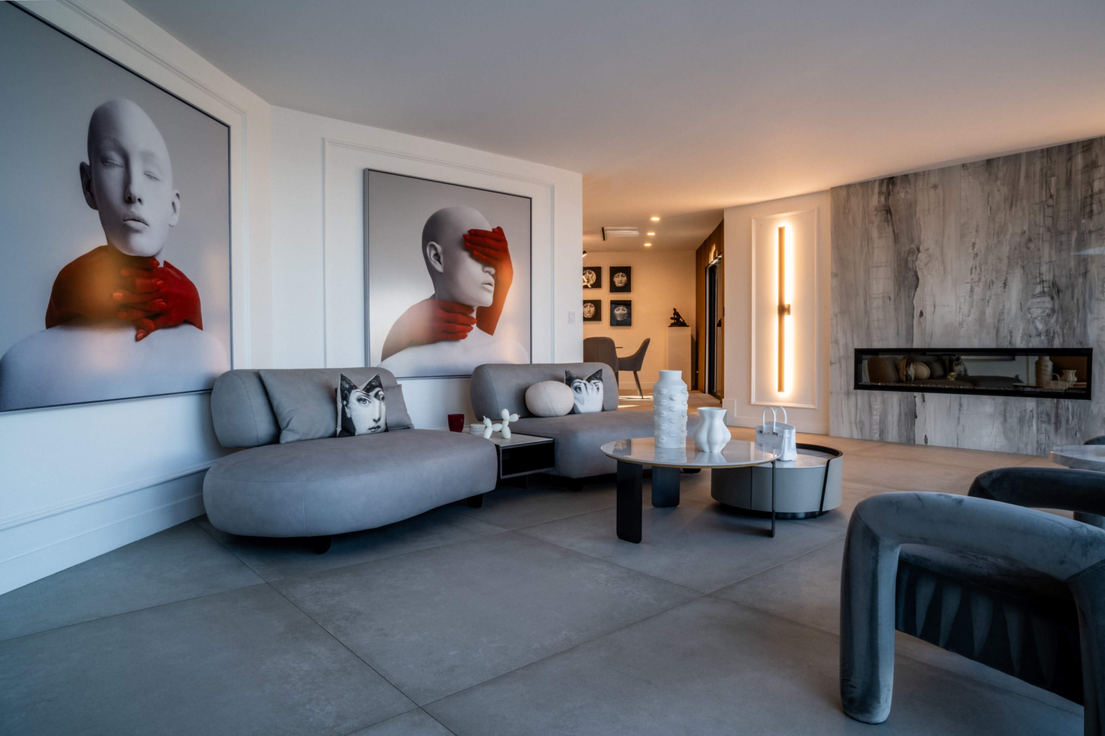 The image shows a modern living room featuring curved furniture, abstract artwork on the walls, and a contemporary fireplace.