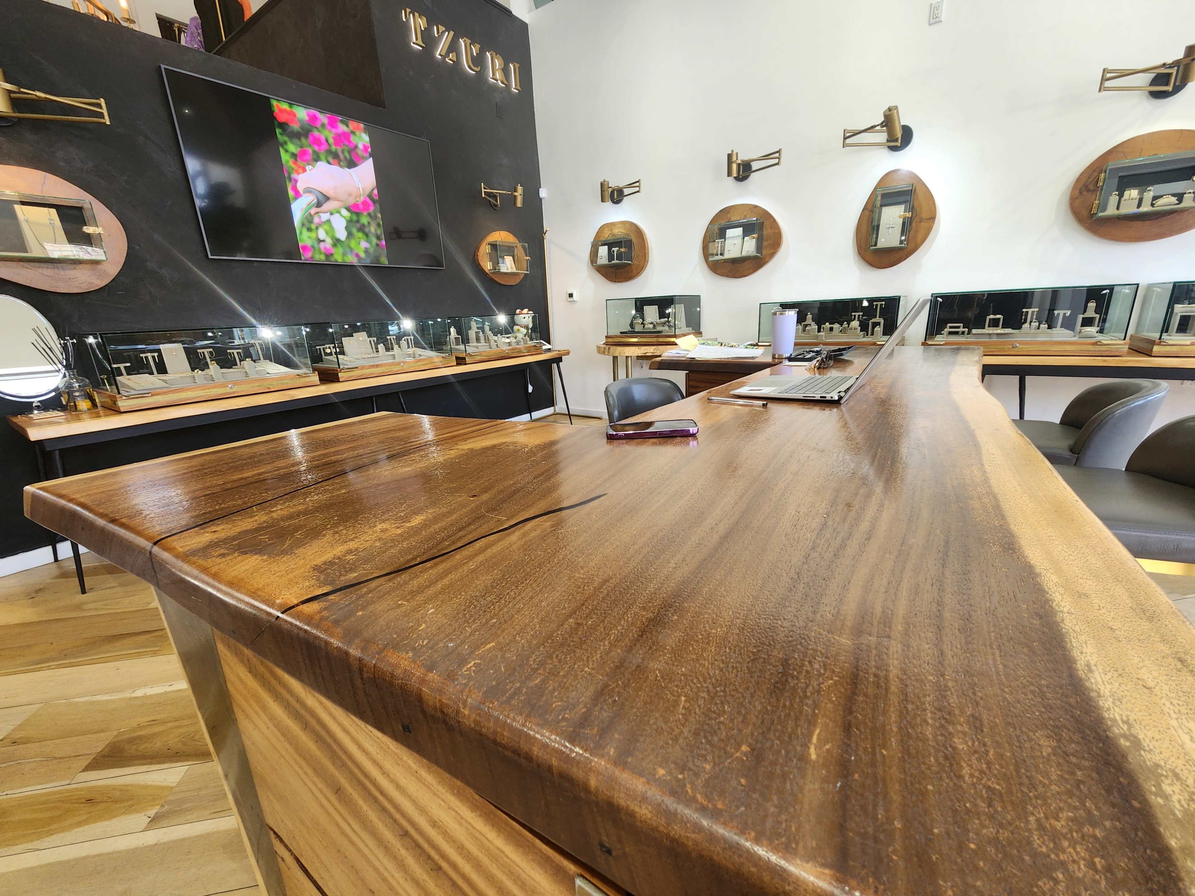 The image shows a modern salon interior with a large wooden countertop and several round mirrors mounted on the wall.
