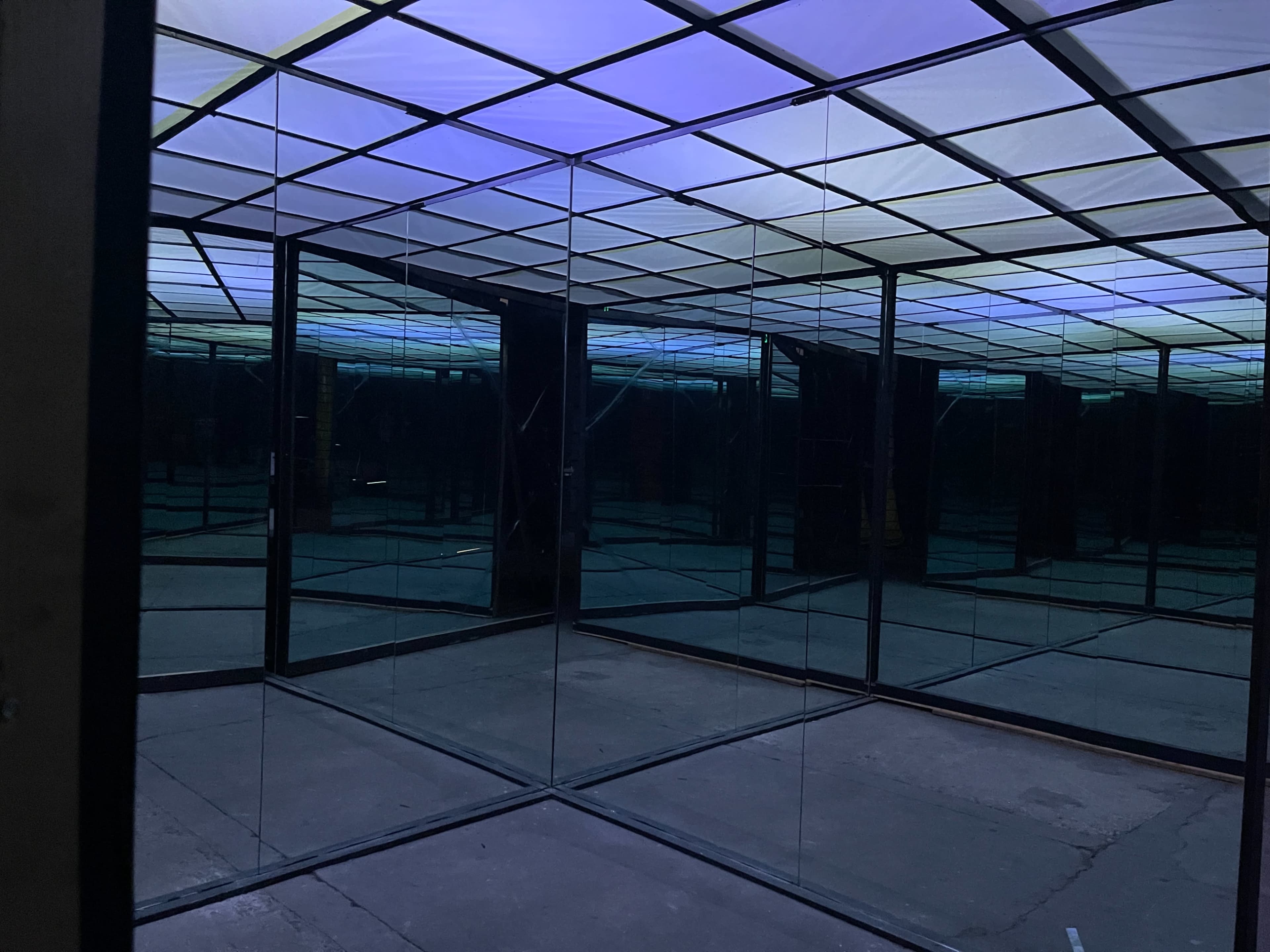 A room with mirrored walls and a ceiling illuminated in shades of blue and purple.