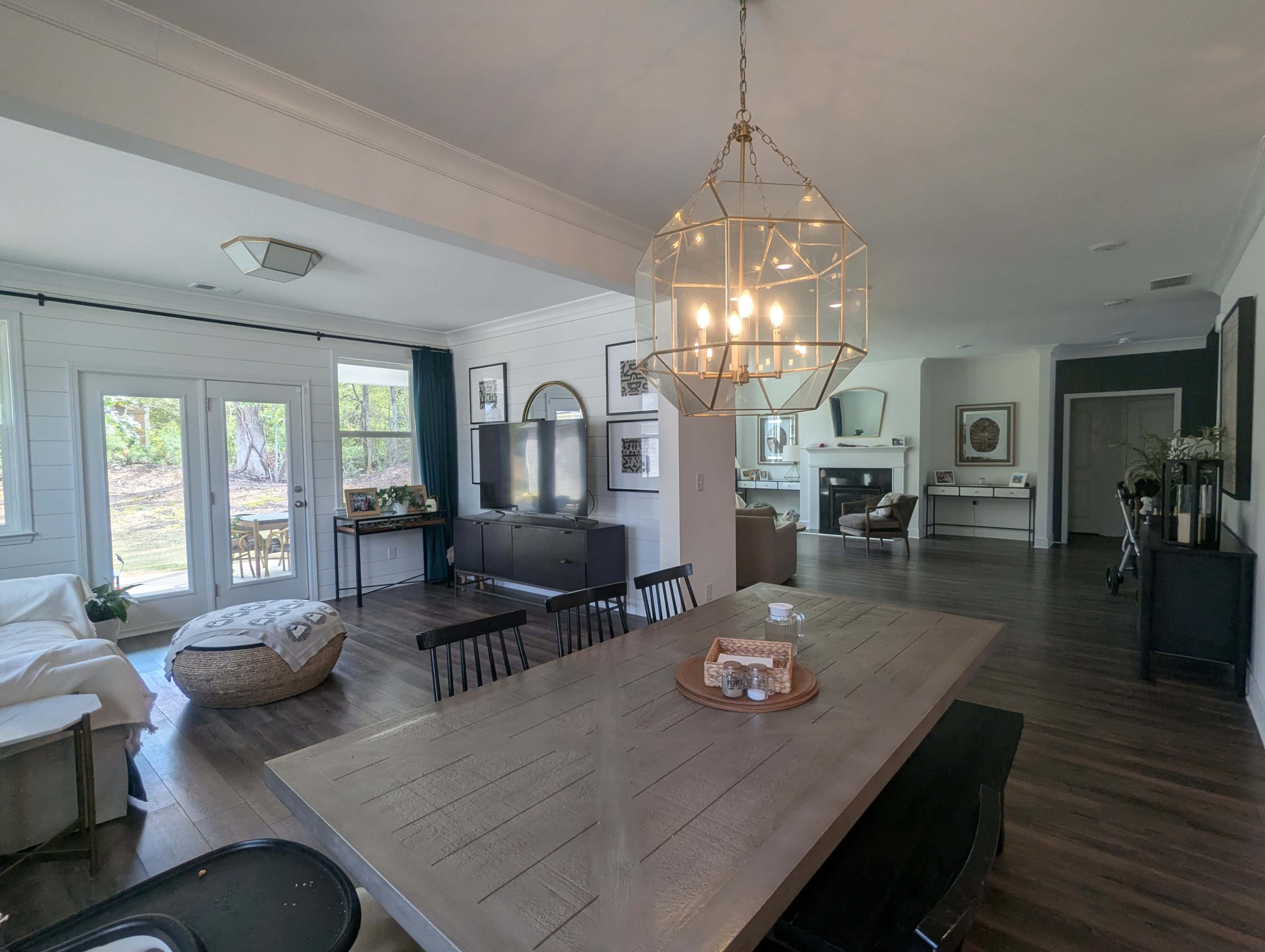 The image shows a spacious, modern living area with a dining table in the foreground, a TV cabinet and seating area in the middle, and a fireplace visible in the background.