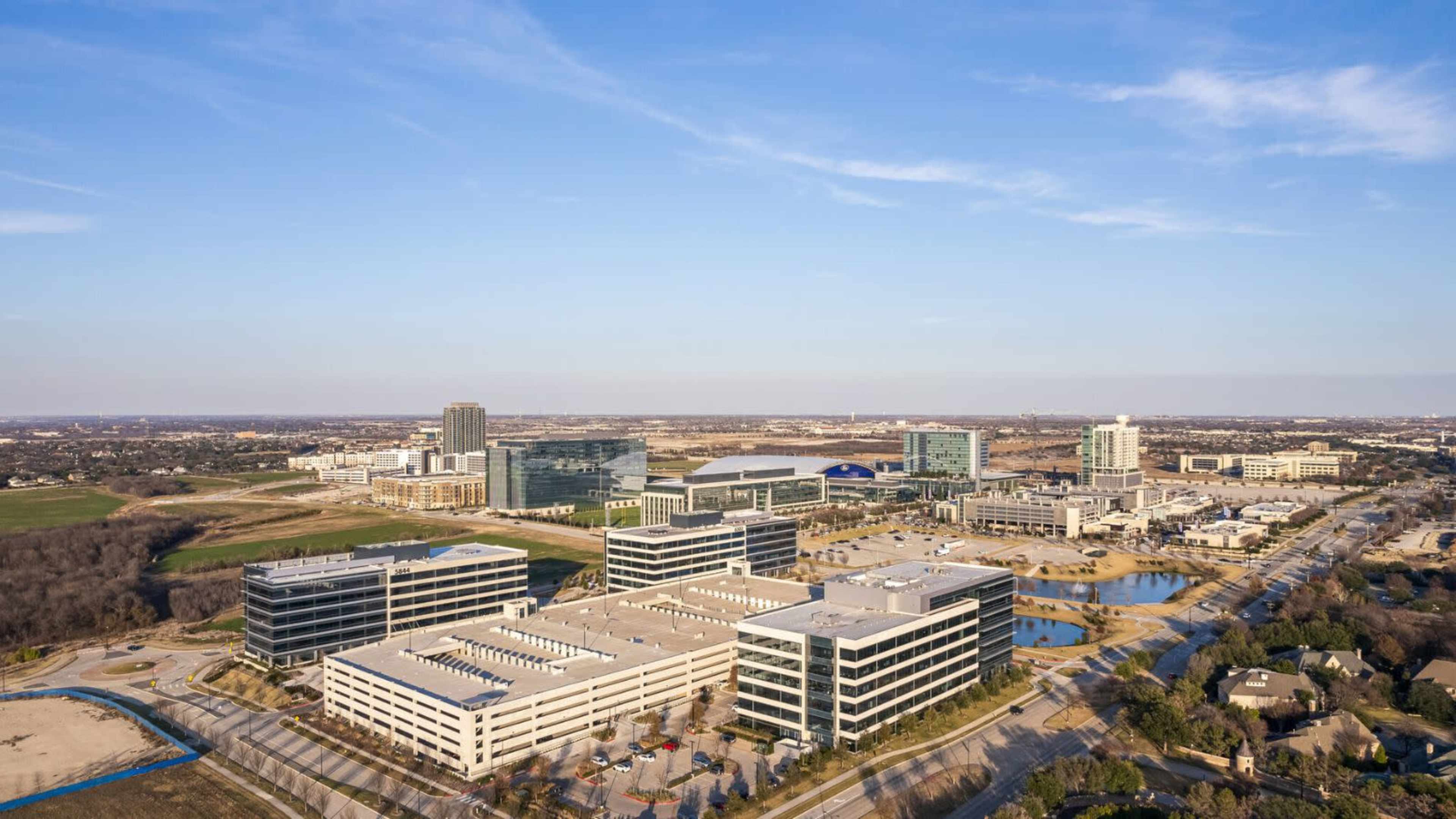 A sprawling urban landscape featuring multiple office buildings and parking structures set against a clear sky.