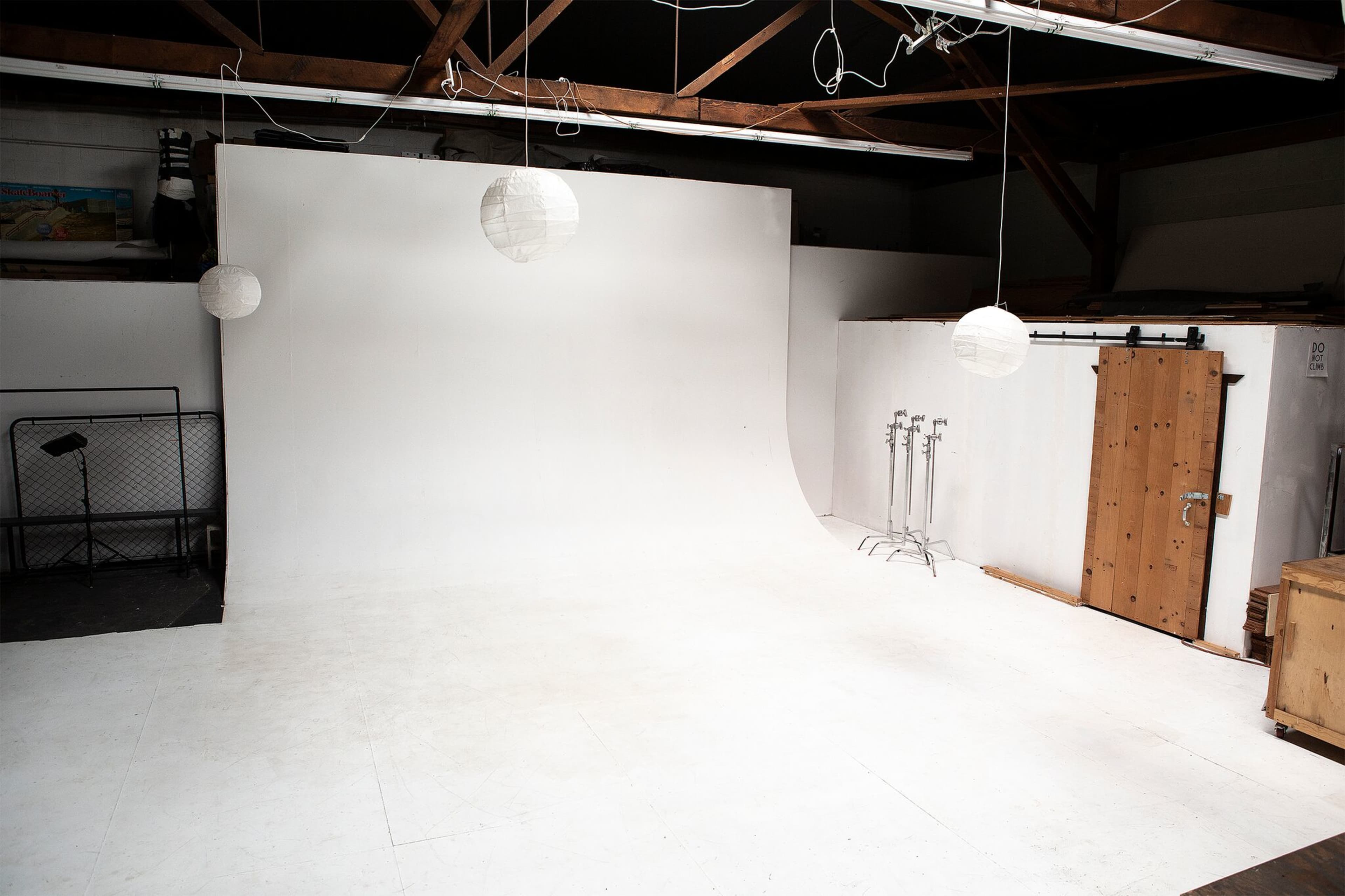 A spacious white backdrop studio with hanging light fixtures and several equipment stands.