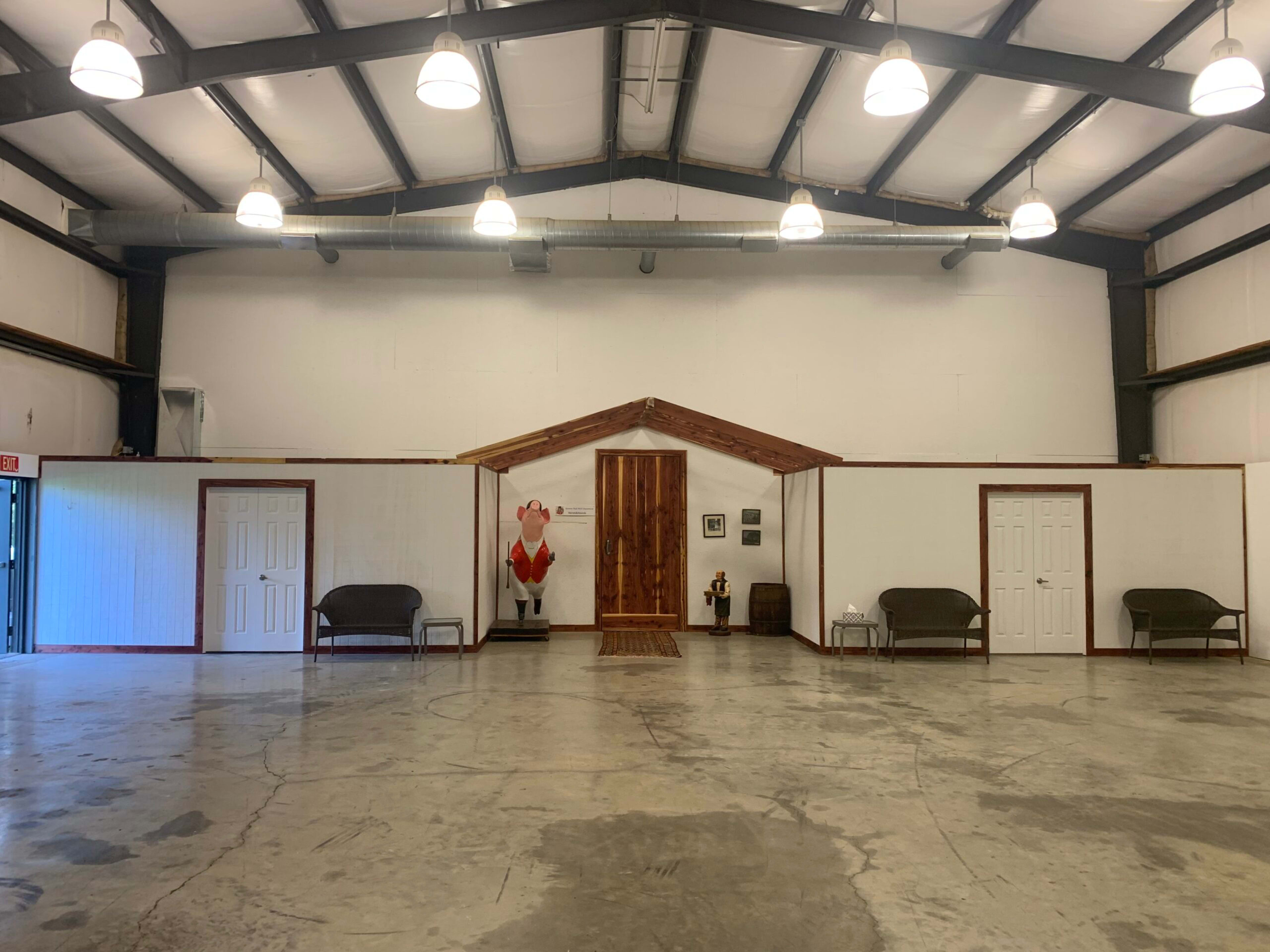 The image shows a large, open space with a high ceiling, featuring multiple doors and two benches along the walls.