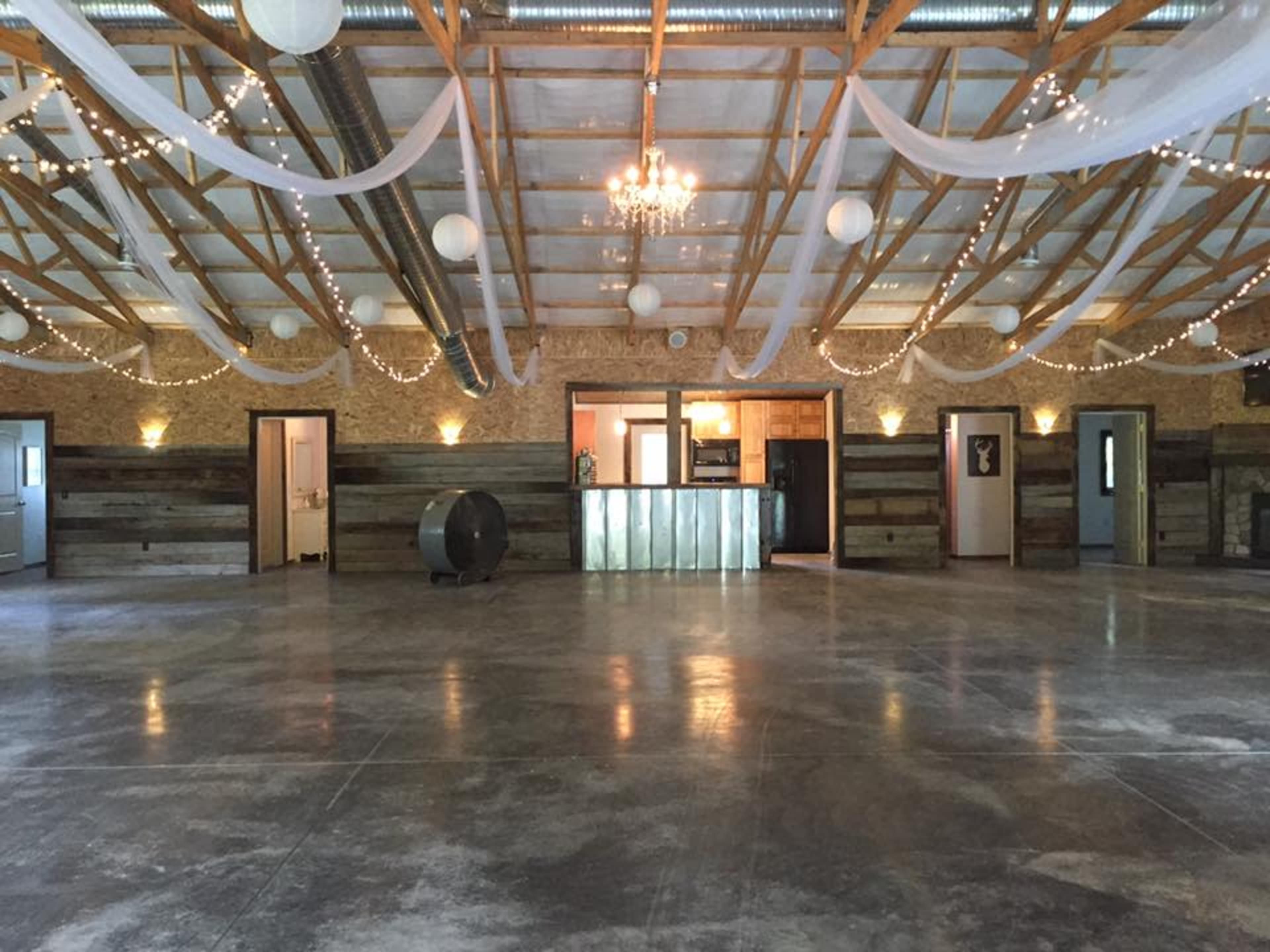 An empty indoor event space with a polished concrete floor, wooden accents on the walls, and decorative lighting.