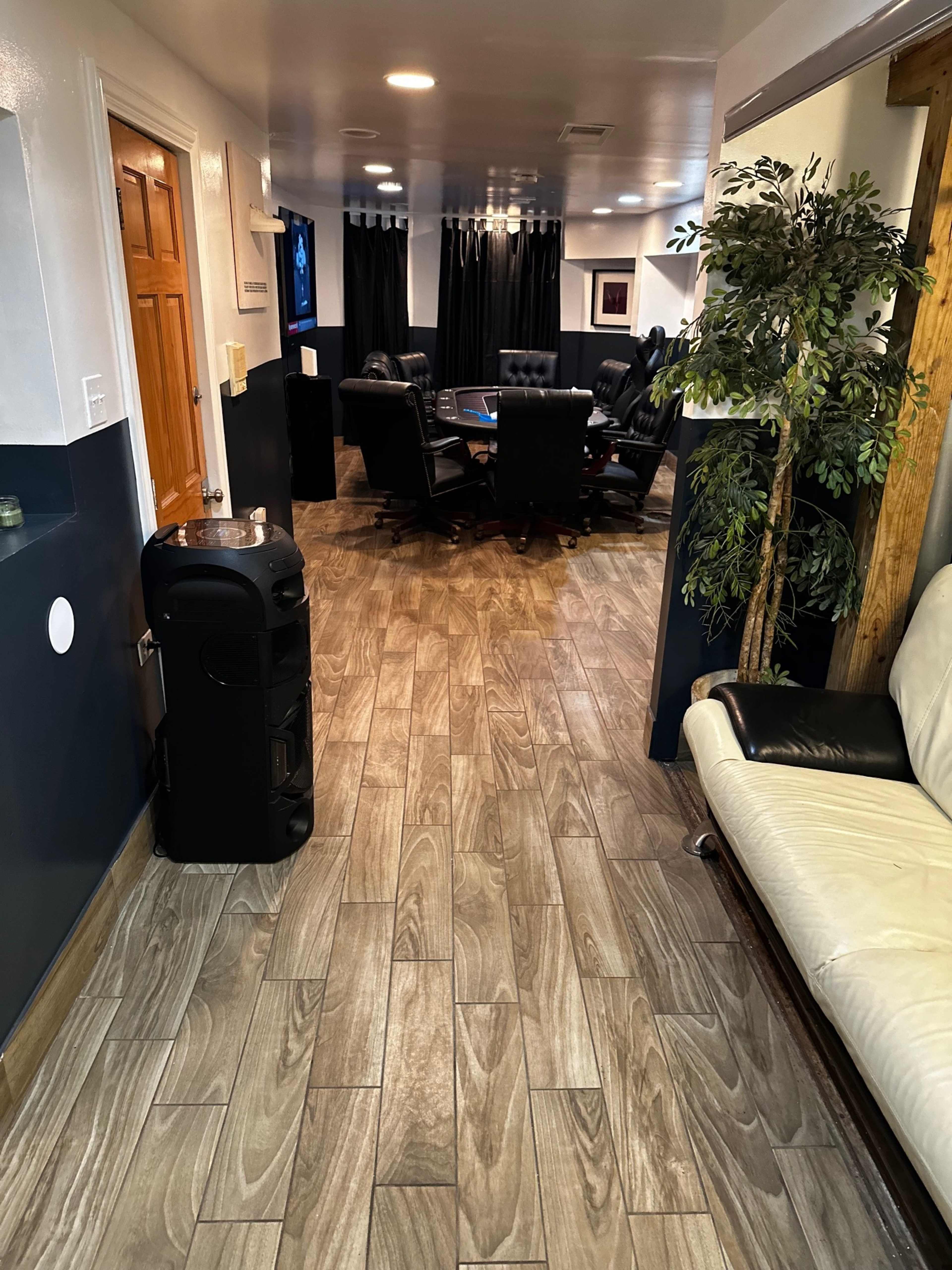 The image shows a well-lit conference room with a large table surrounded by black chairs, a water cooler, and a sofa along the wall.