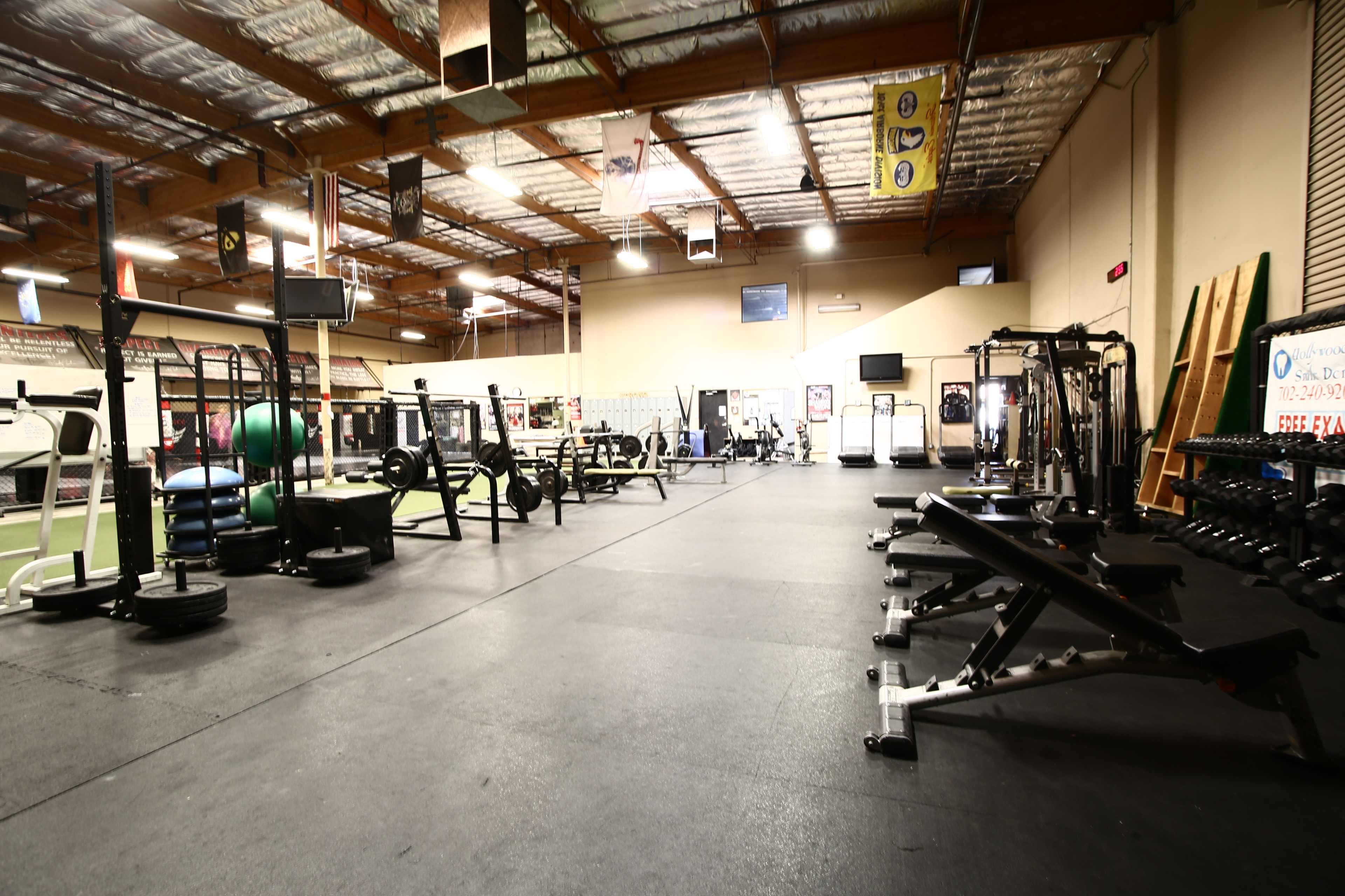 A spacious gym interior equipped with various weightlifting and exercise machines, along with exercise mats and fitness equipment.