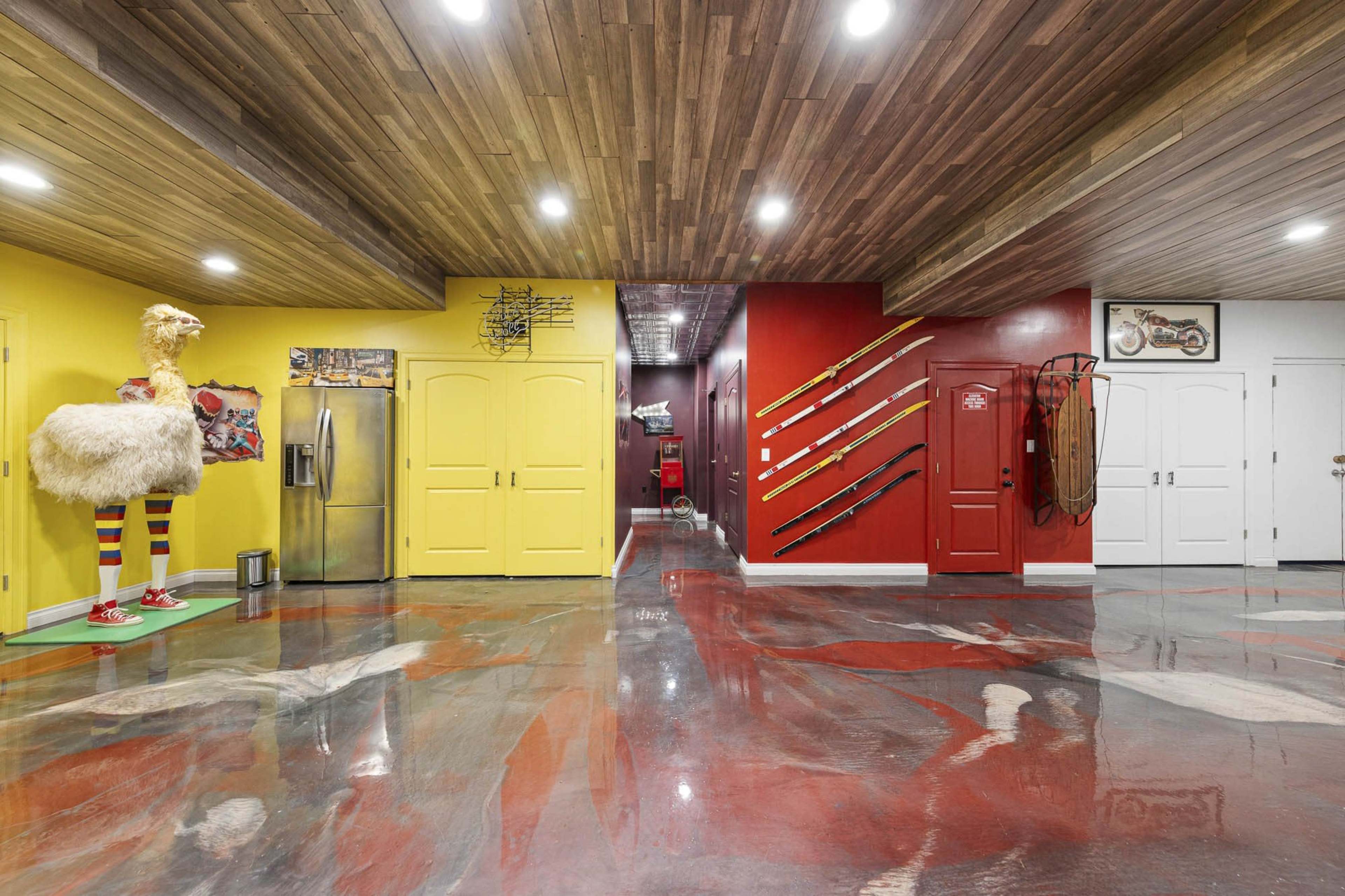 A brightly colored hallway with yellow and red walls, polished concrete floors, and various decorative objects, including a mannequin and wall-mounted items.