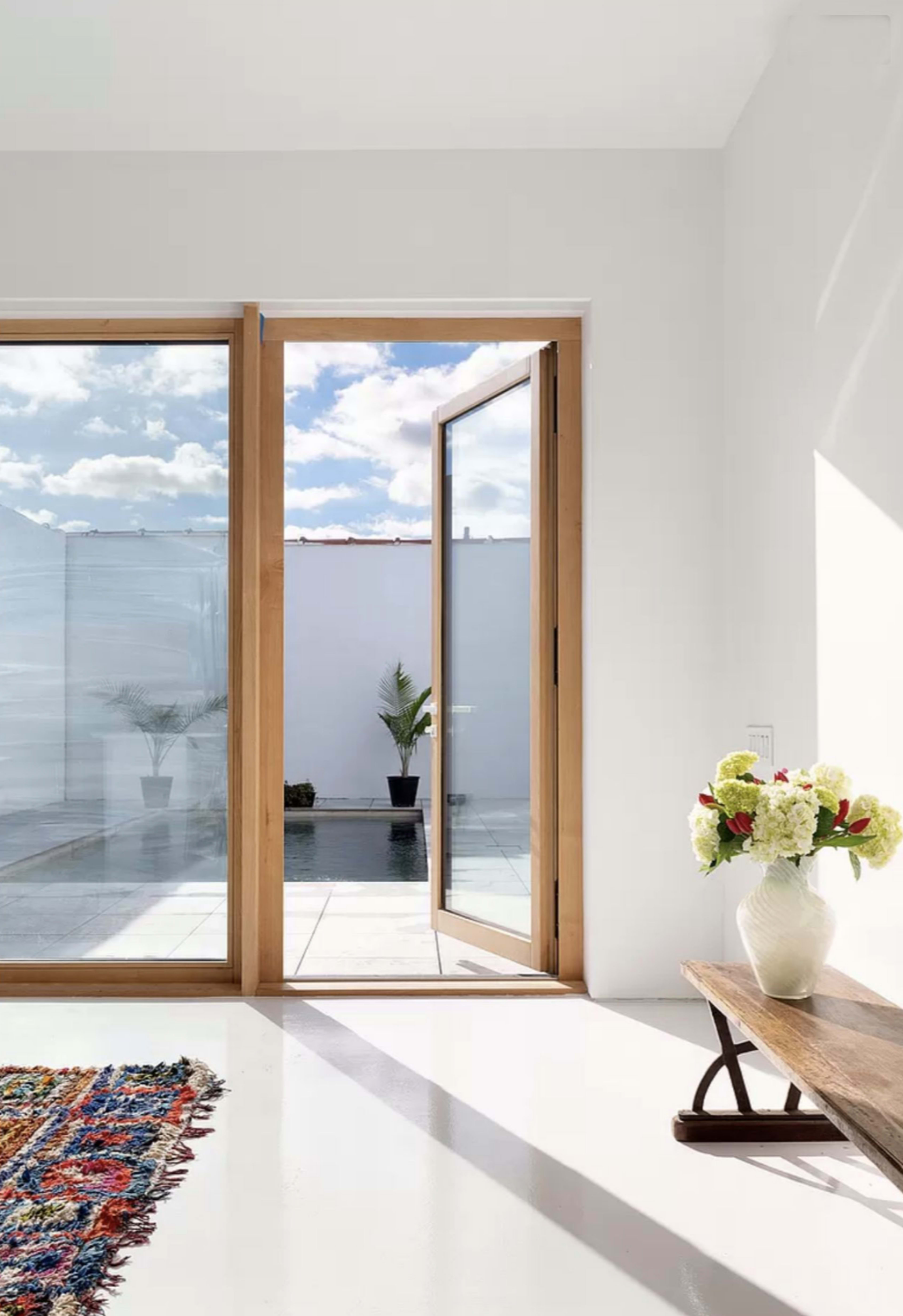 A spacious interior features large glass doors opening to a small pool area with potted plants.