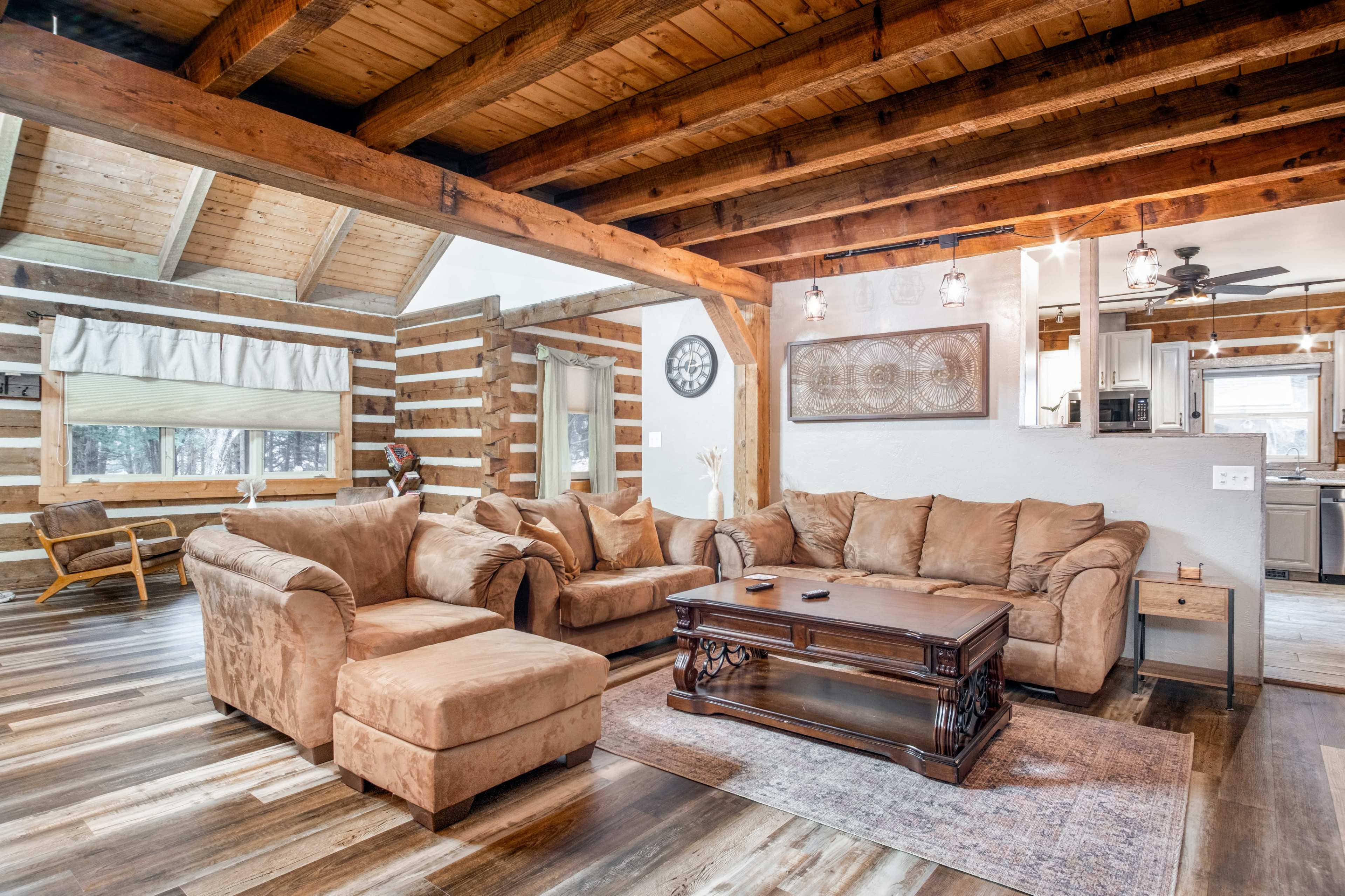 A spacious living room features a sectional sofa, a wooden coffee table, and exposed wooden beams in the ceiling.