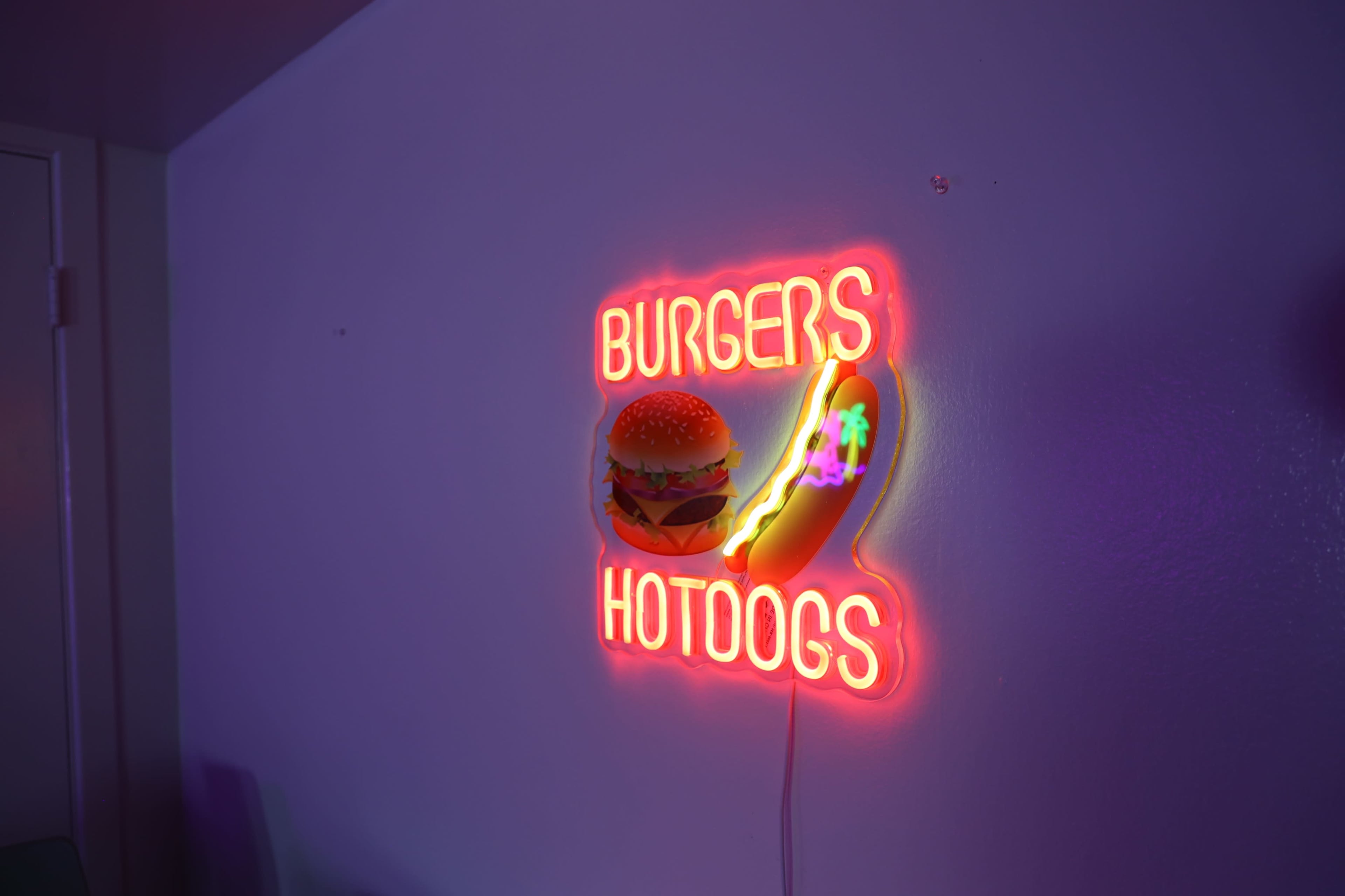 A neon sign displays the words "BURGERS" and "HOTDOGS" alongside graphic images of a burger and a hotdog.