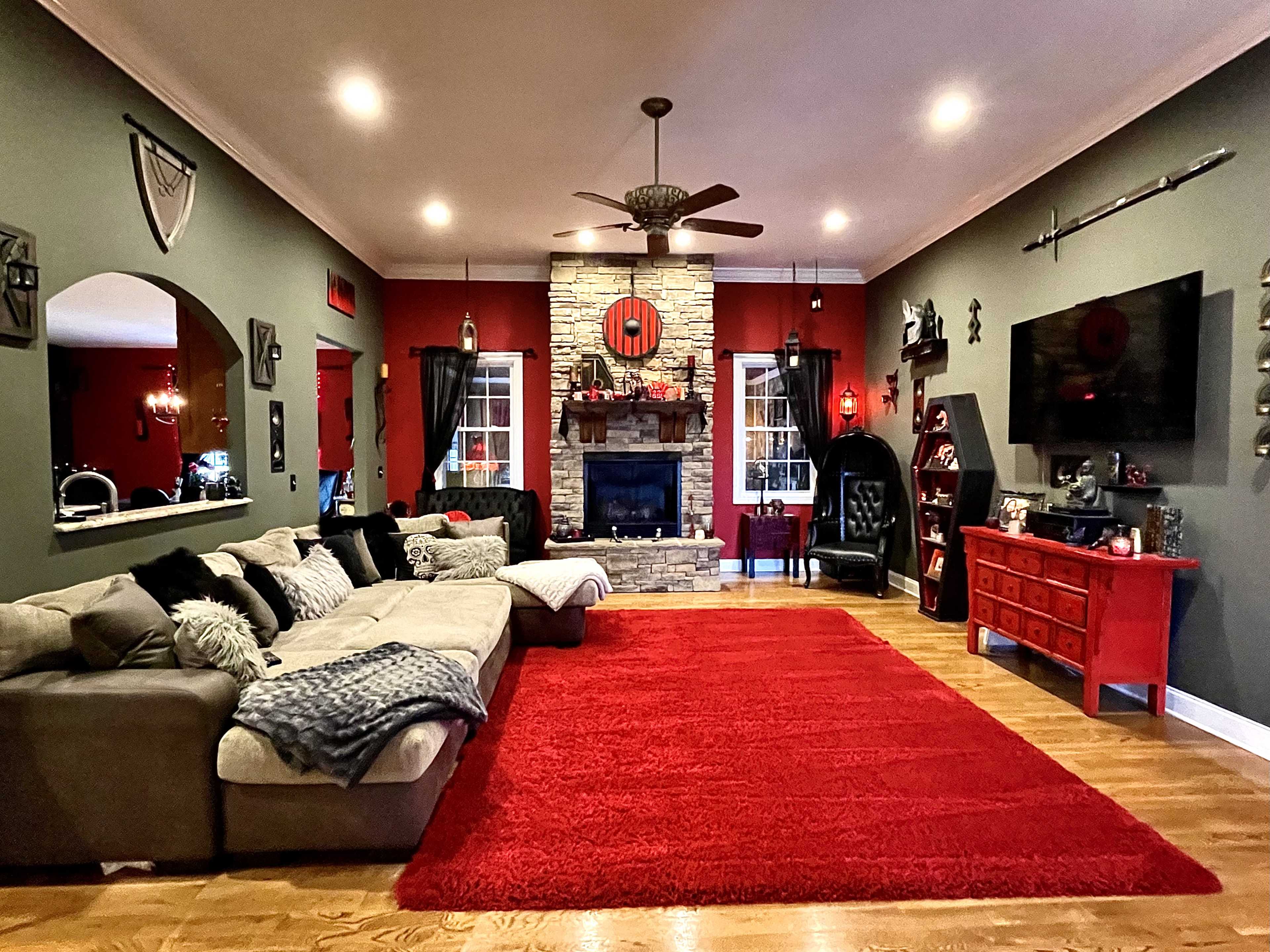 The living room features a large sectional sofa, a red area rug, a stone fireplace, and a combination of dark and light wall colors.