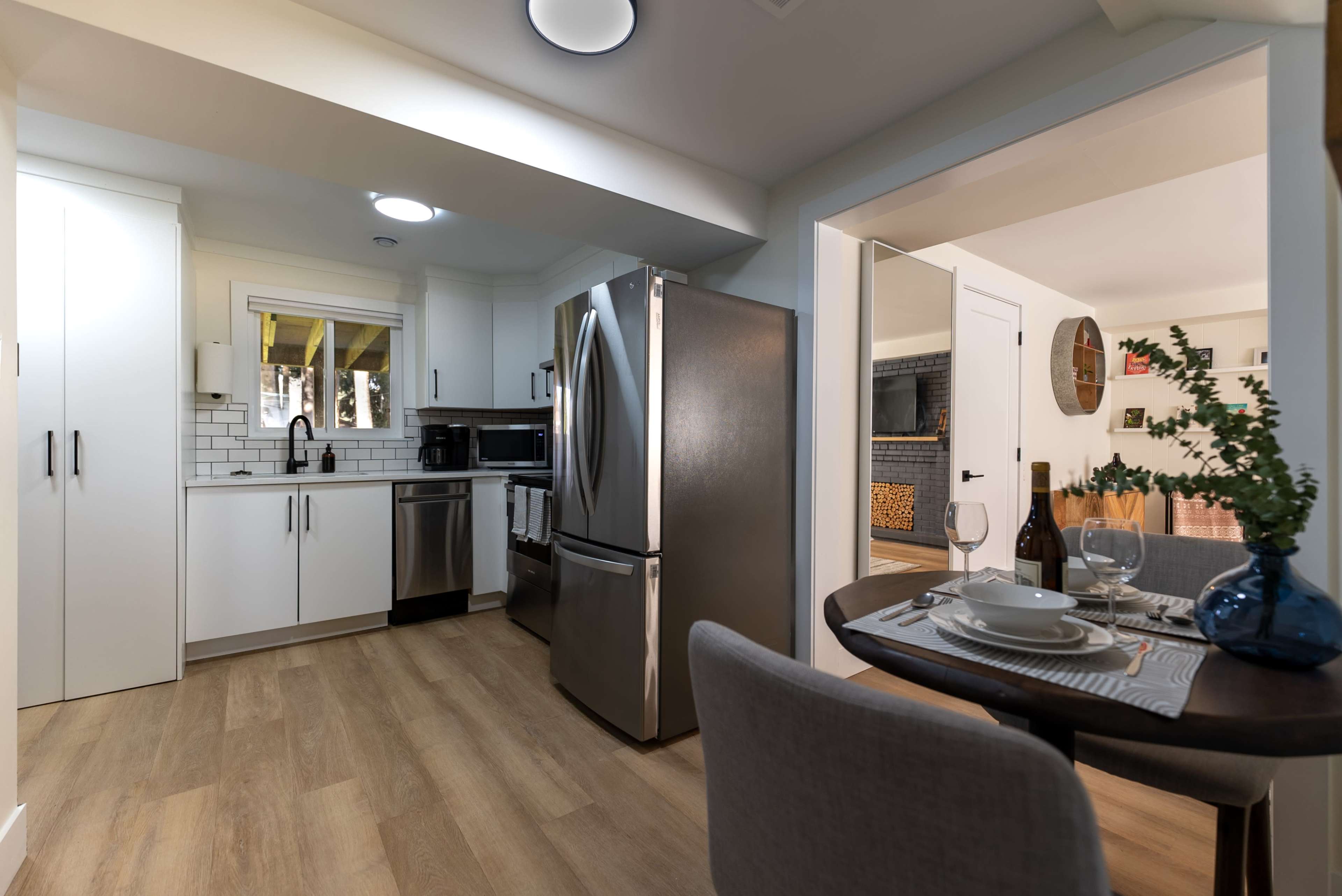 A modern kitchen with stainless steel appliances, white cabinets, and a dining area featuring a small table set for two.