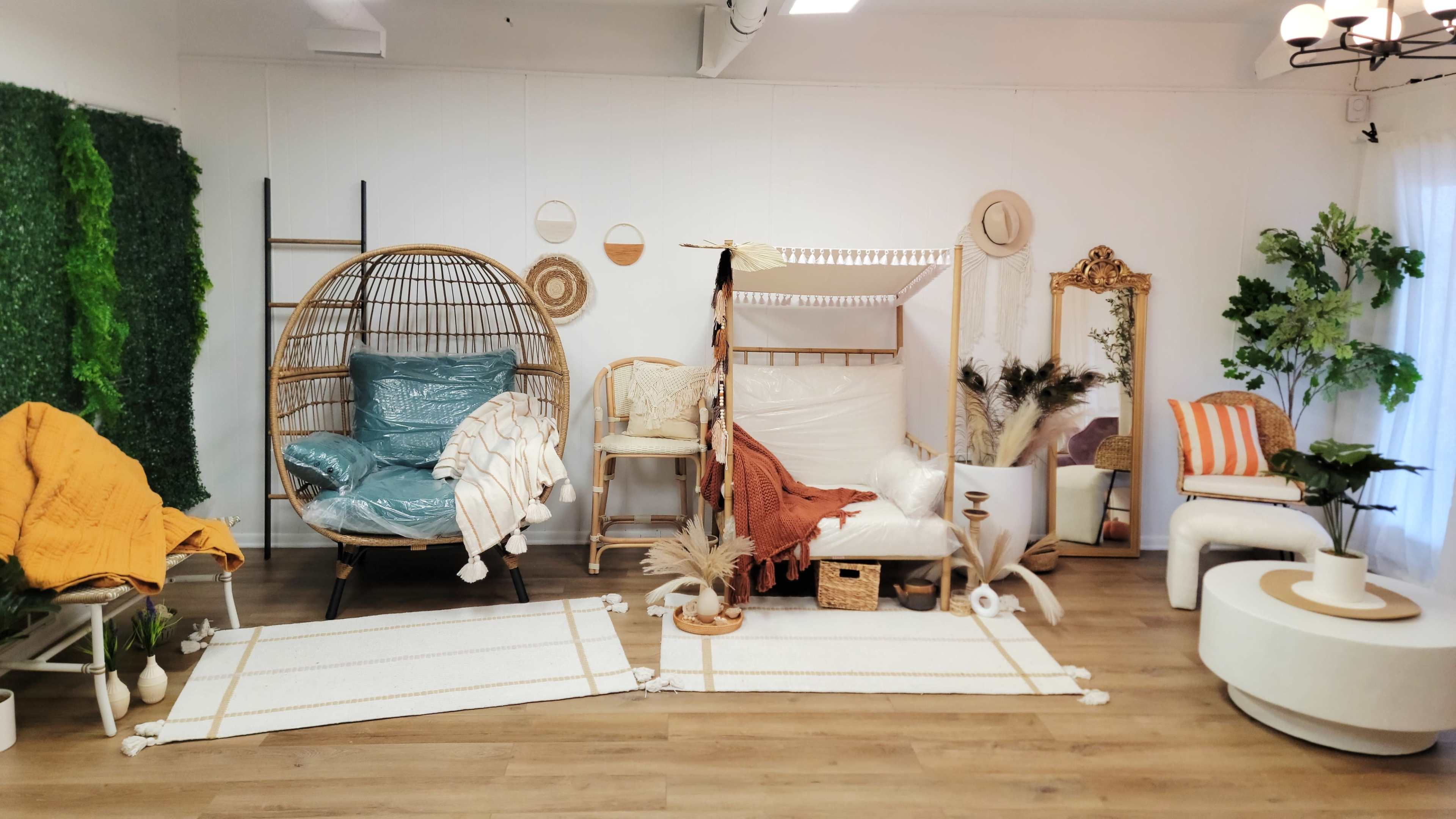 A stylish interior setup featuring various seating arrangements, decorative plants, and textiles in a well-lit room.