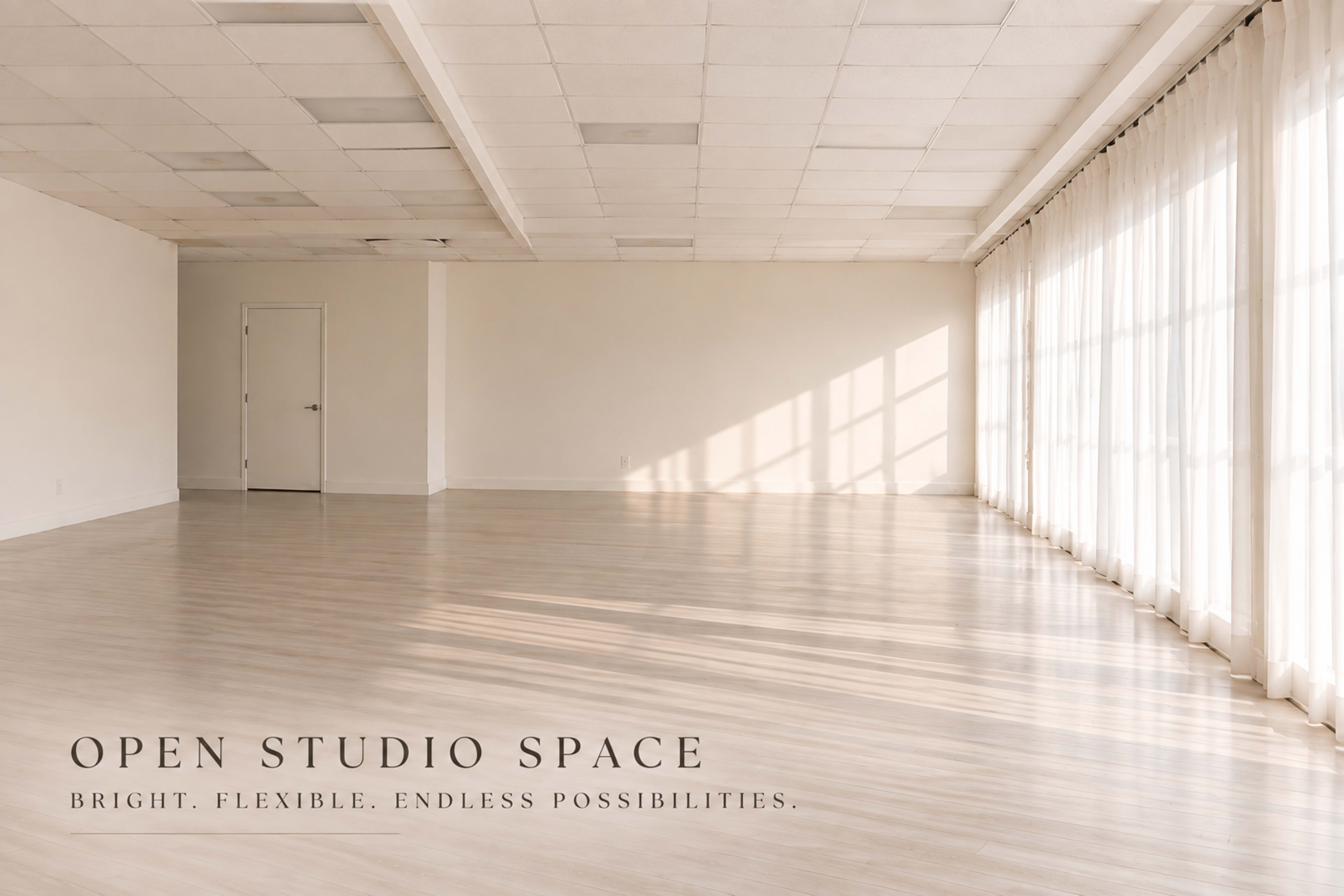 The image depicts a spacious, well-lit studio with large windows and a polished wooden floor.