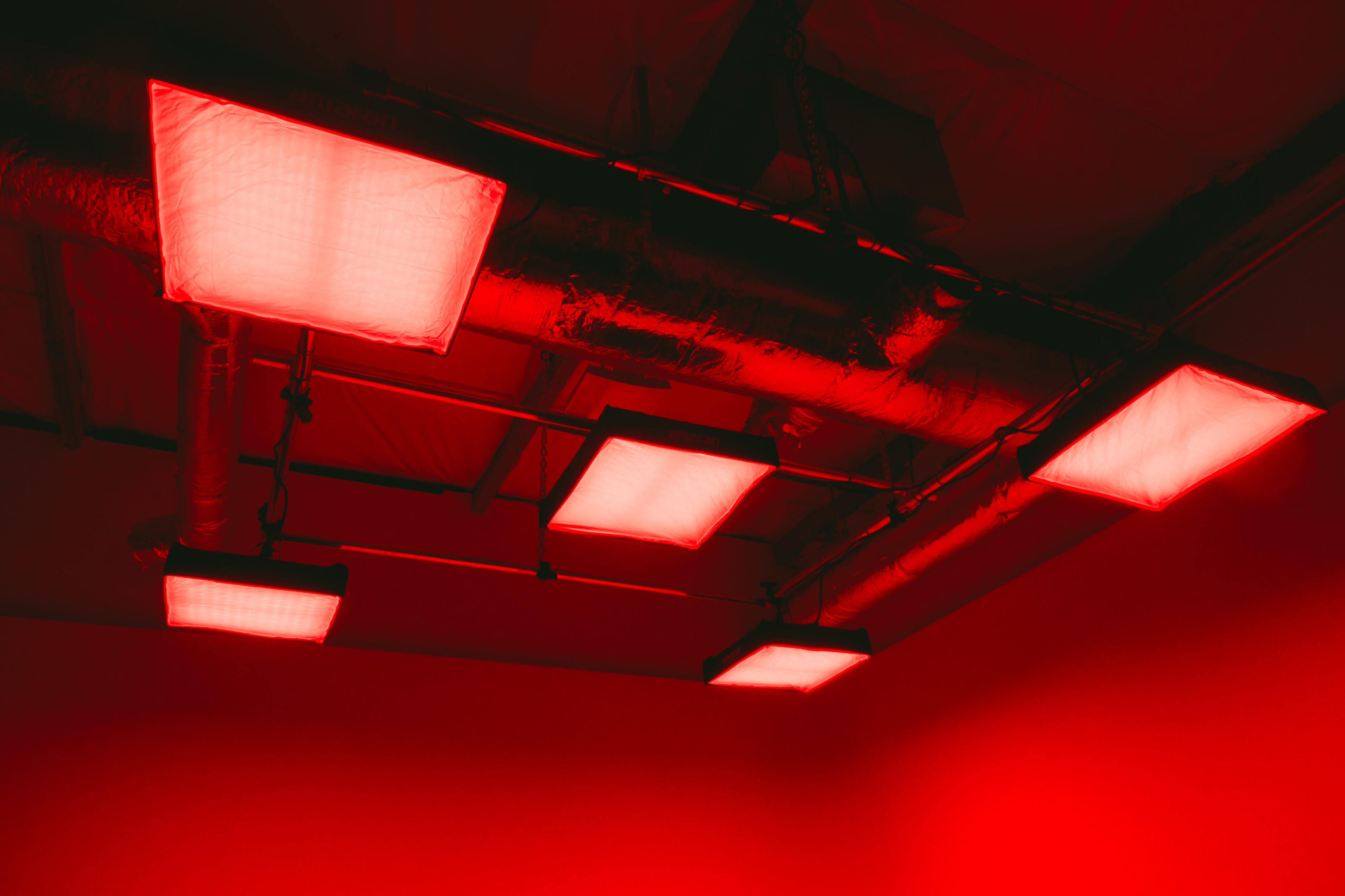 A ceiling with red-lit fluorescent panels against a red background.