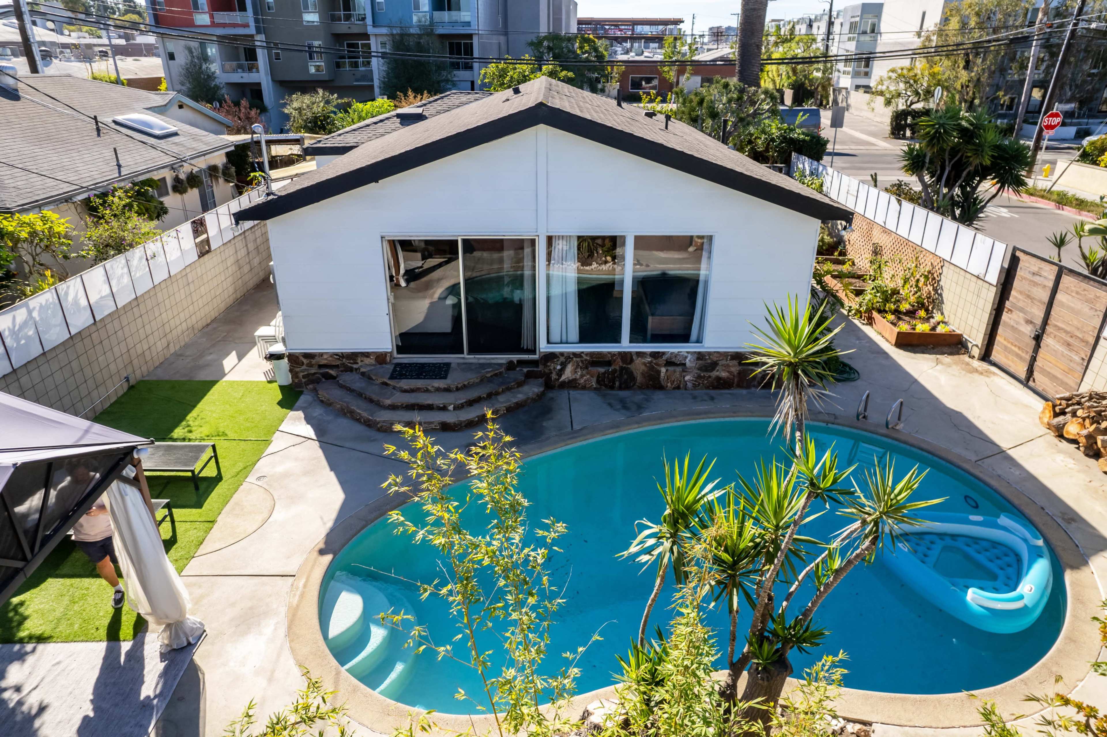 A house with a swimming pool, surrounded by greenery, and outdoor seating areas.