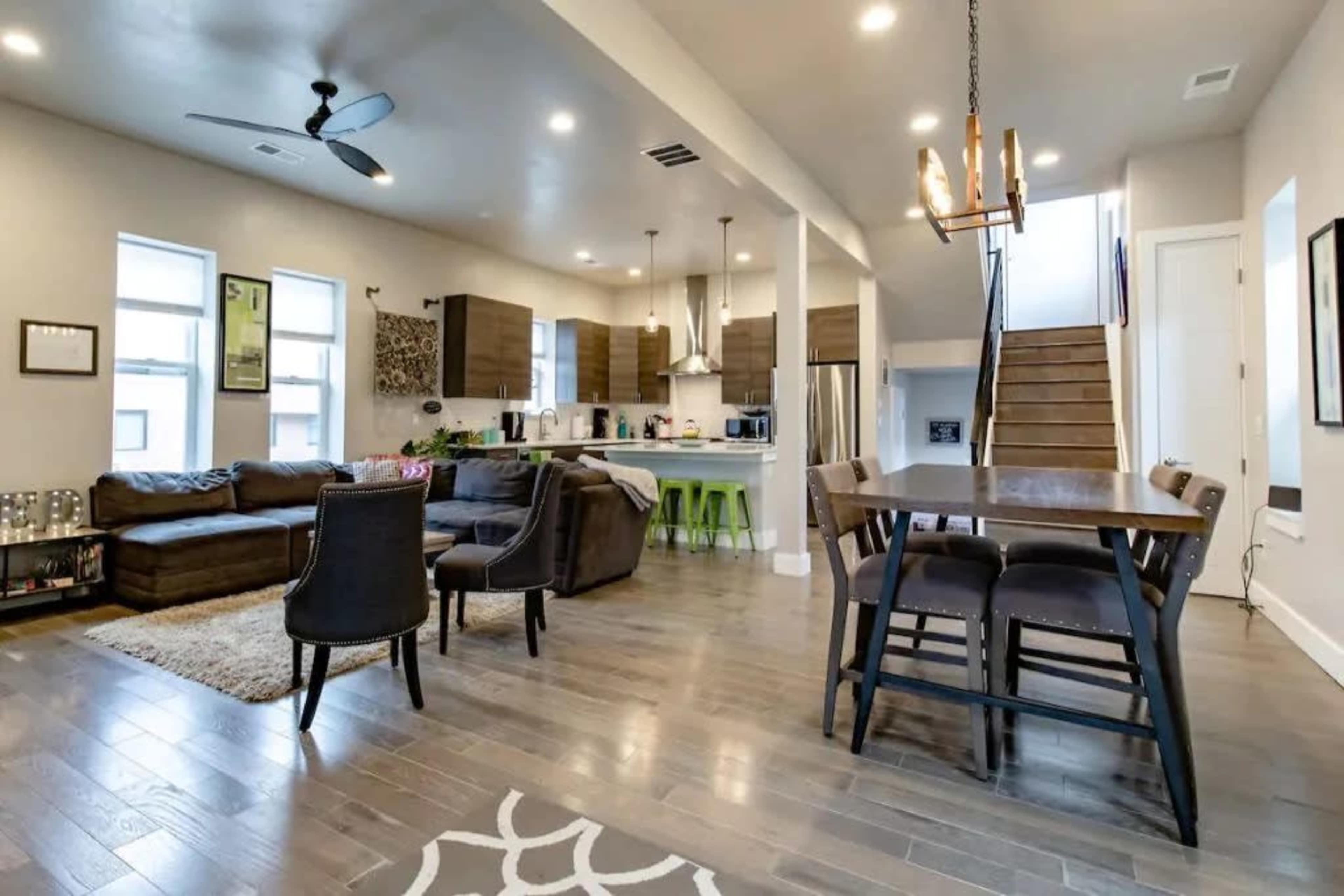 A modern open-concept living and dining area with a sofa, dining table, and kitchen in a well-lit space.