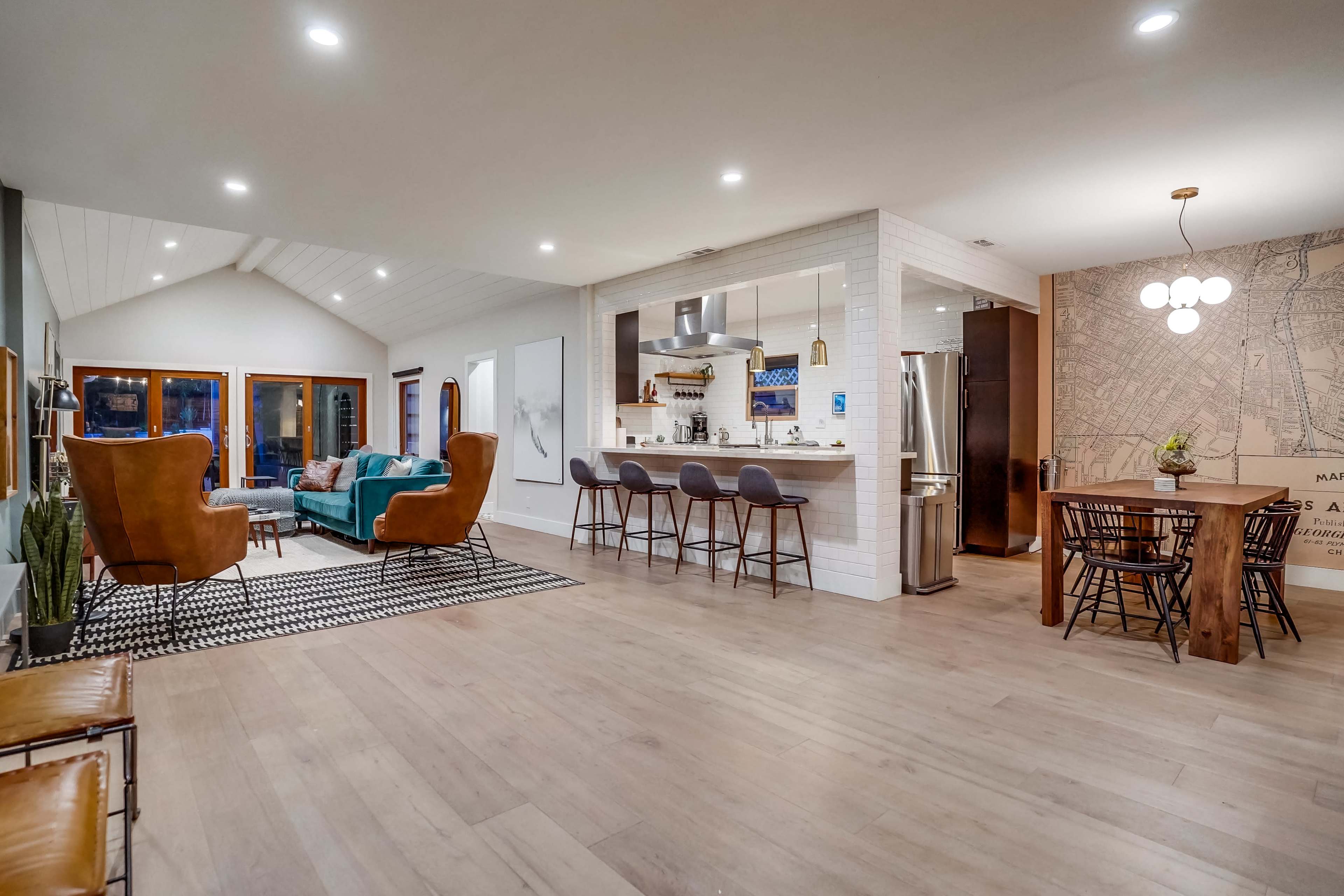 A modern, open-concept living area with a kitchen, dining space, and seating area that features large windows and contemporary furnishings.