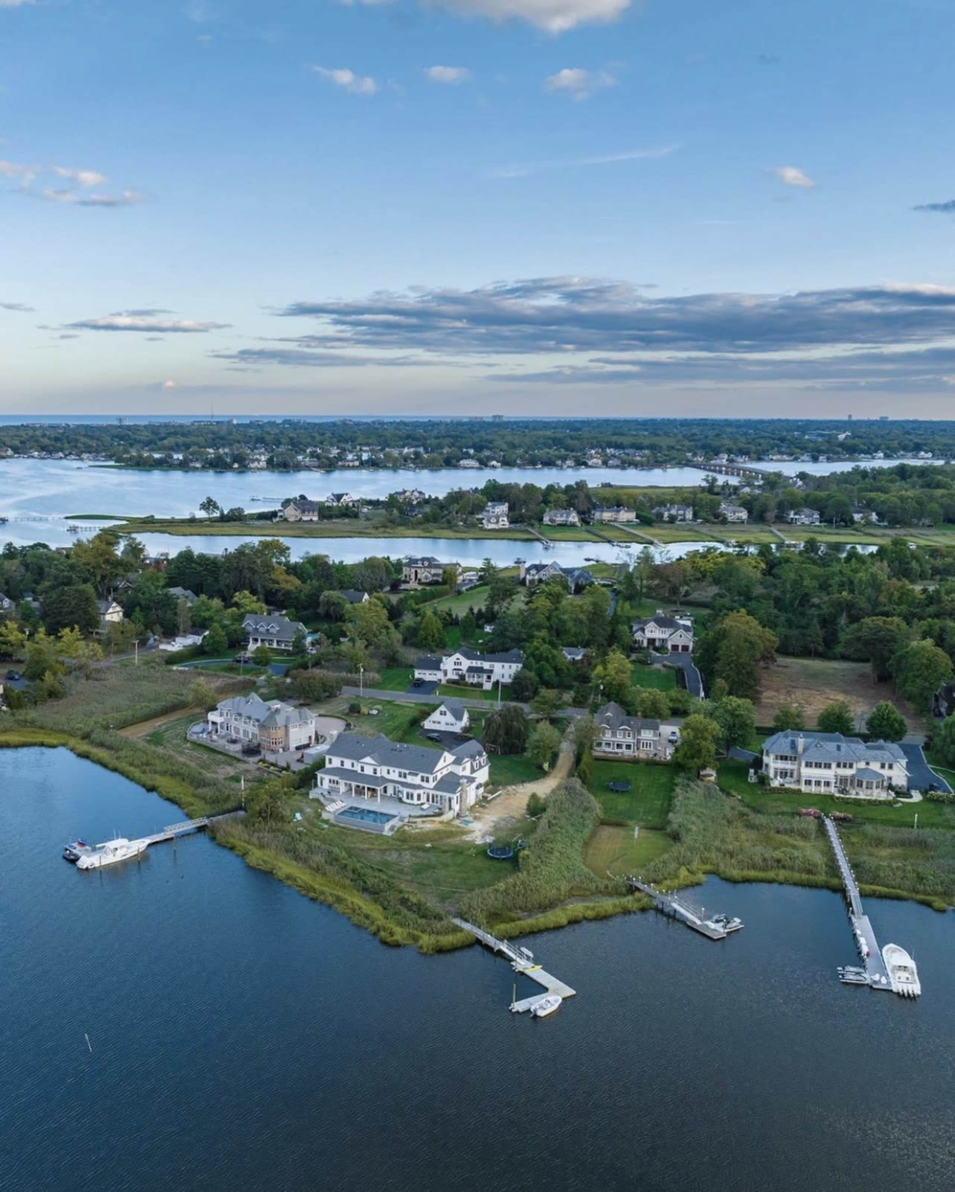 A coastal suburban area with houses along the waterfront and several docks extending into the water.