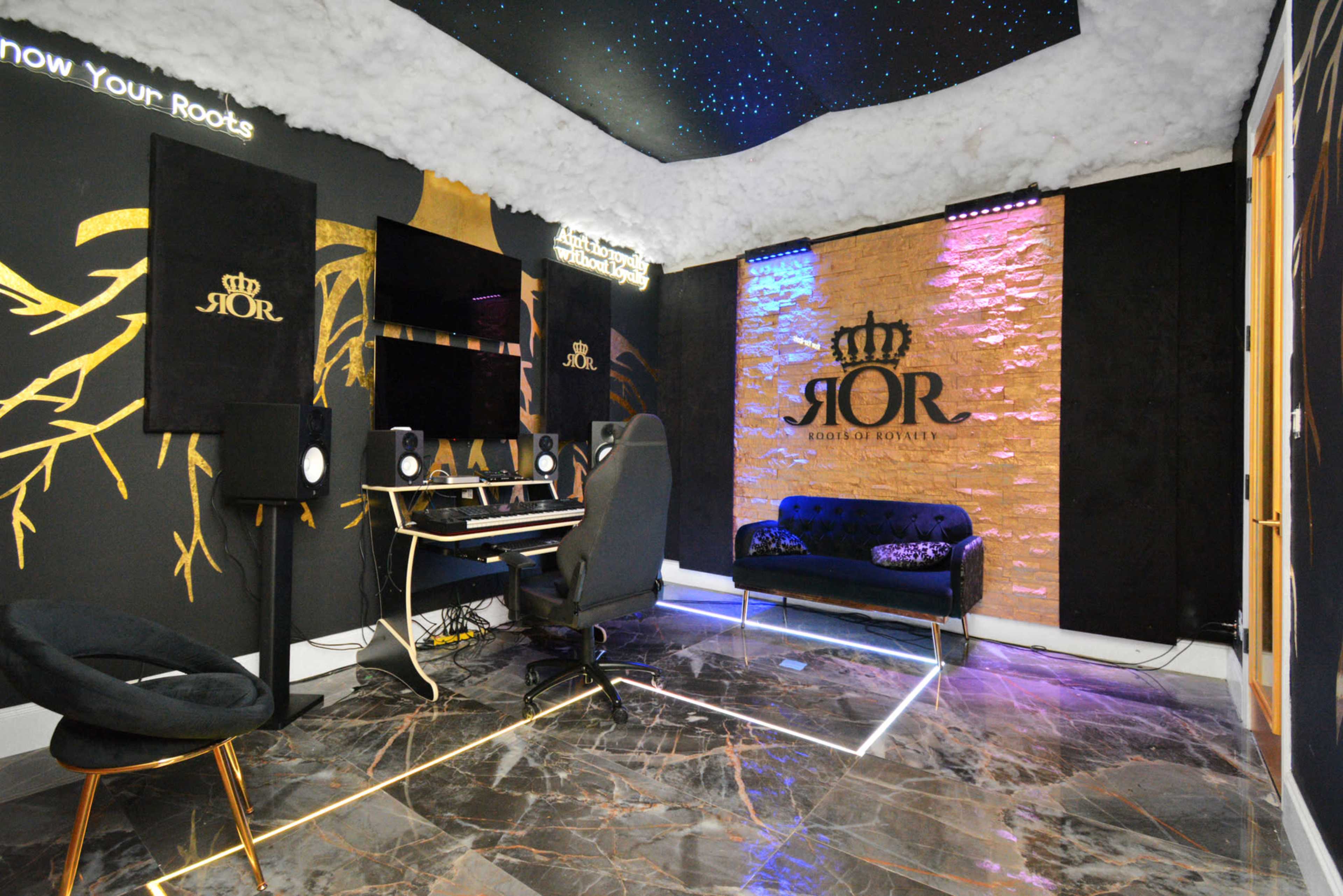 The image features a modern recording studio with dark walls, a stylish black couch, and a computer workstation equipped with audio equipment, all under a starry ceiling.