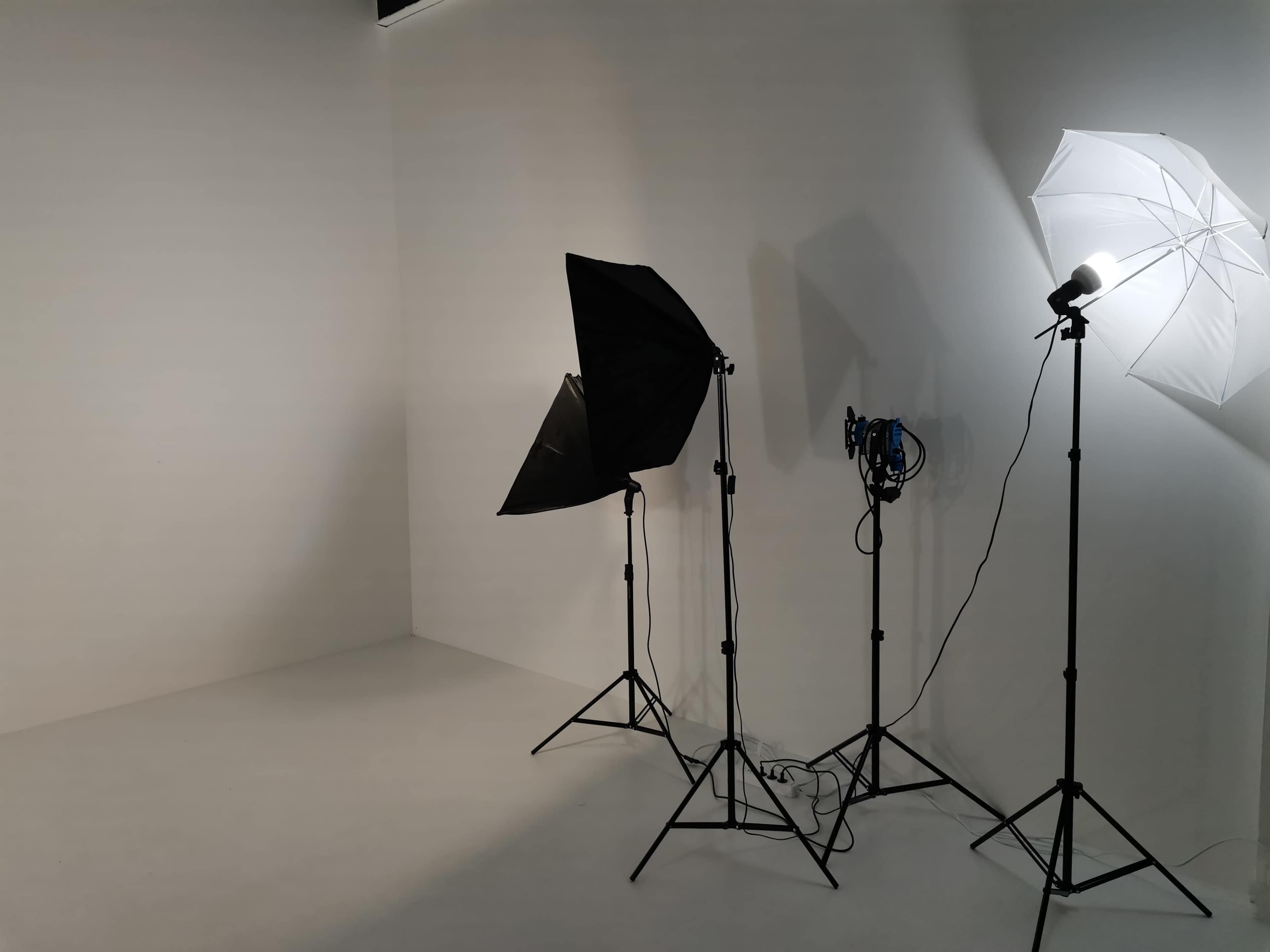 A photography studio setup with two light stands and a blank backdrop.