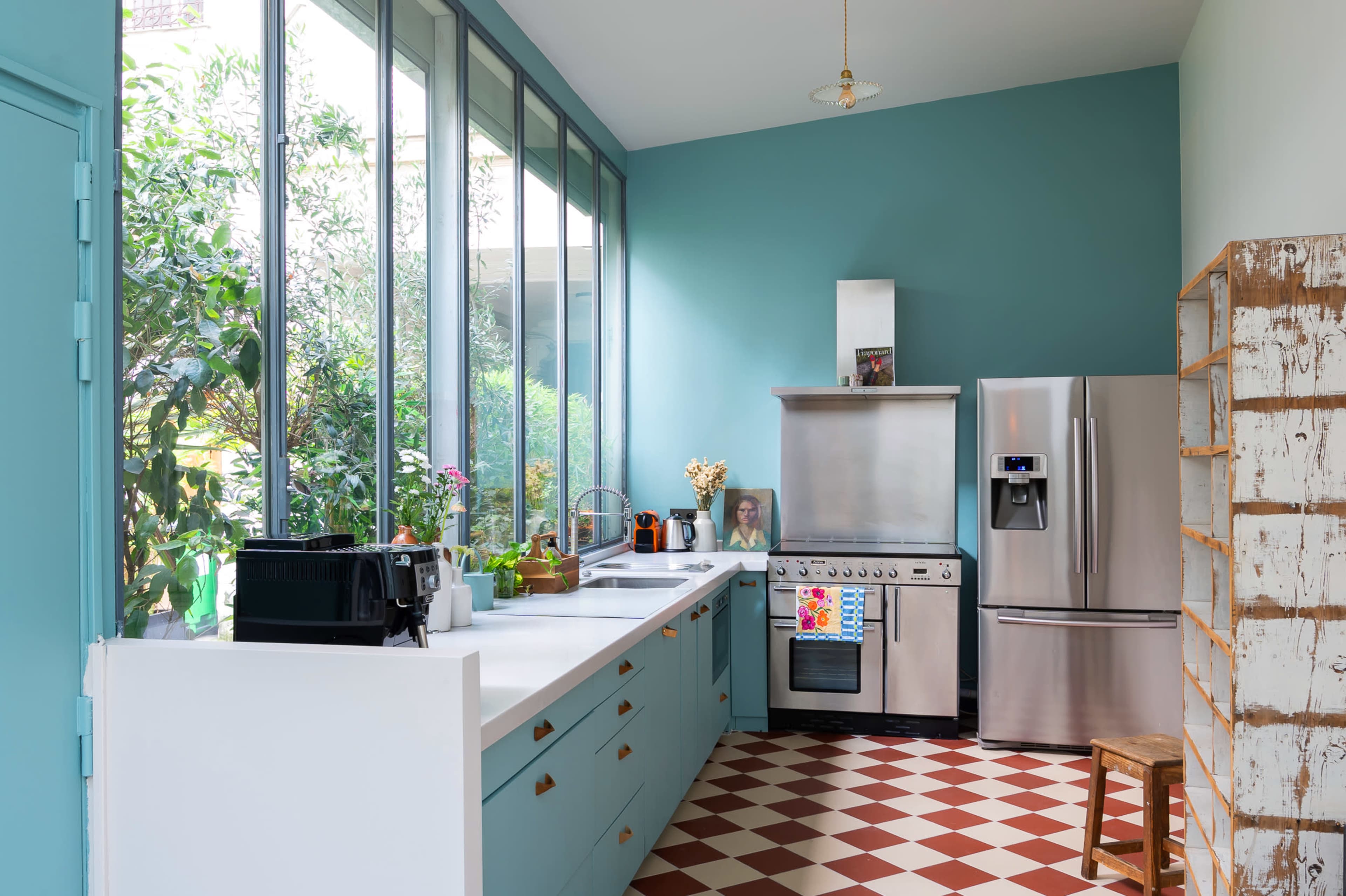The kitchen features blue walls, a combination of modern appliances, and a large window that provides natural light.