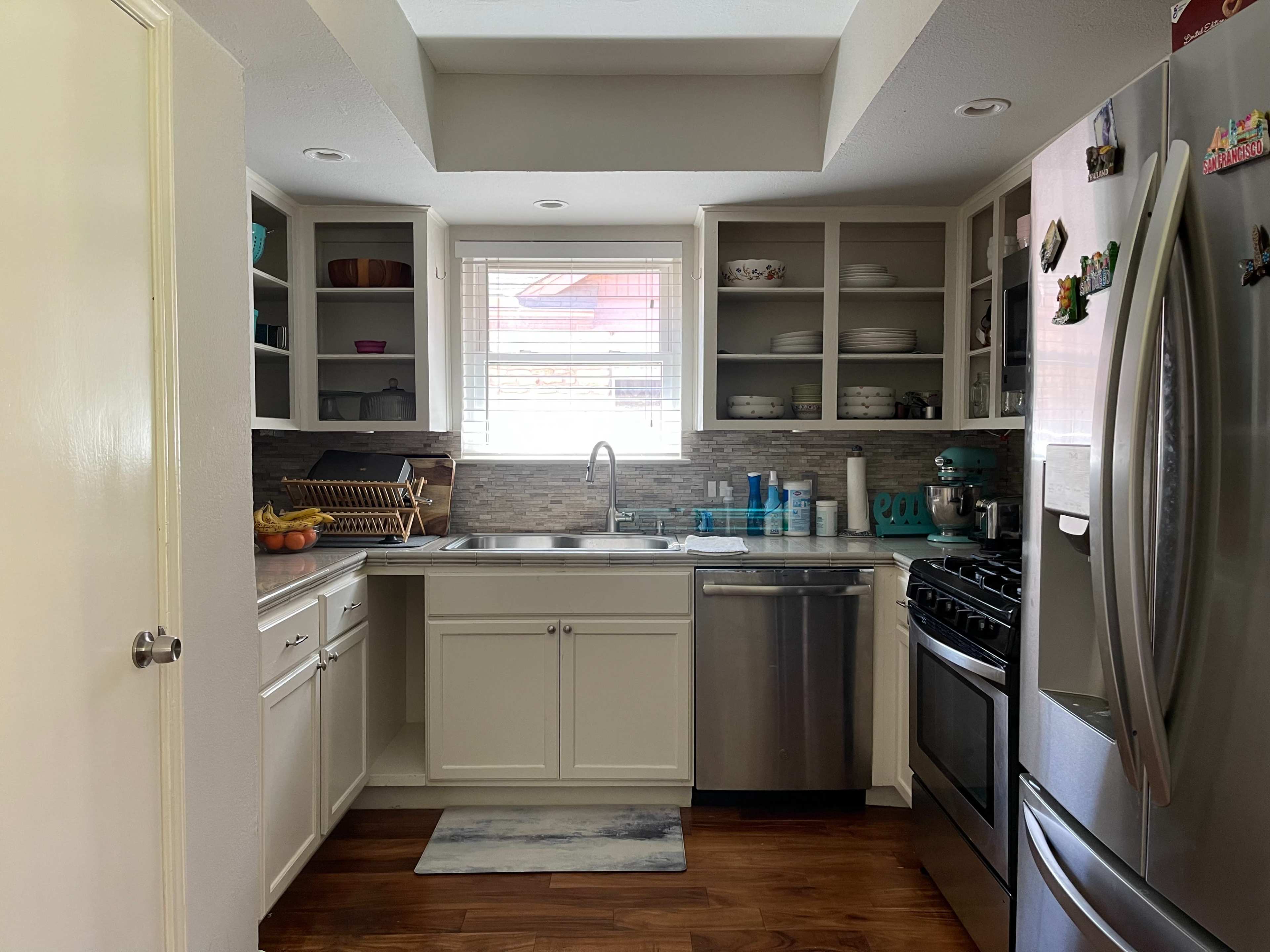 A modern kitchen with light cabinetry, stainless steel appliances, and a window above the sink.