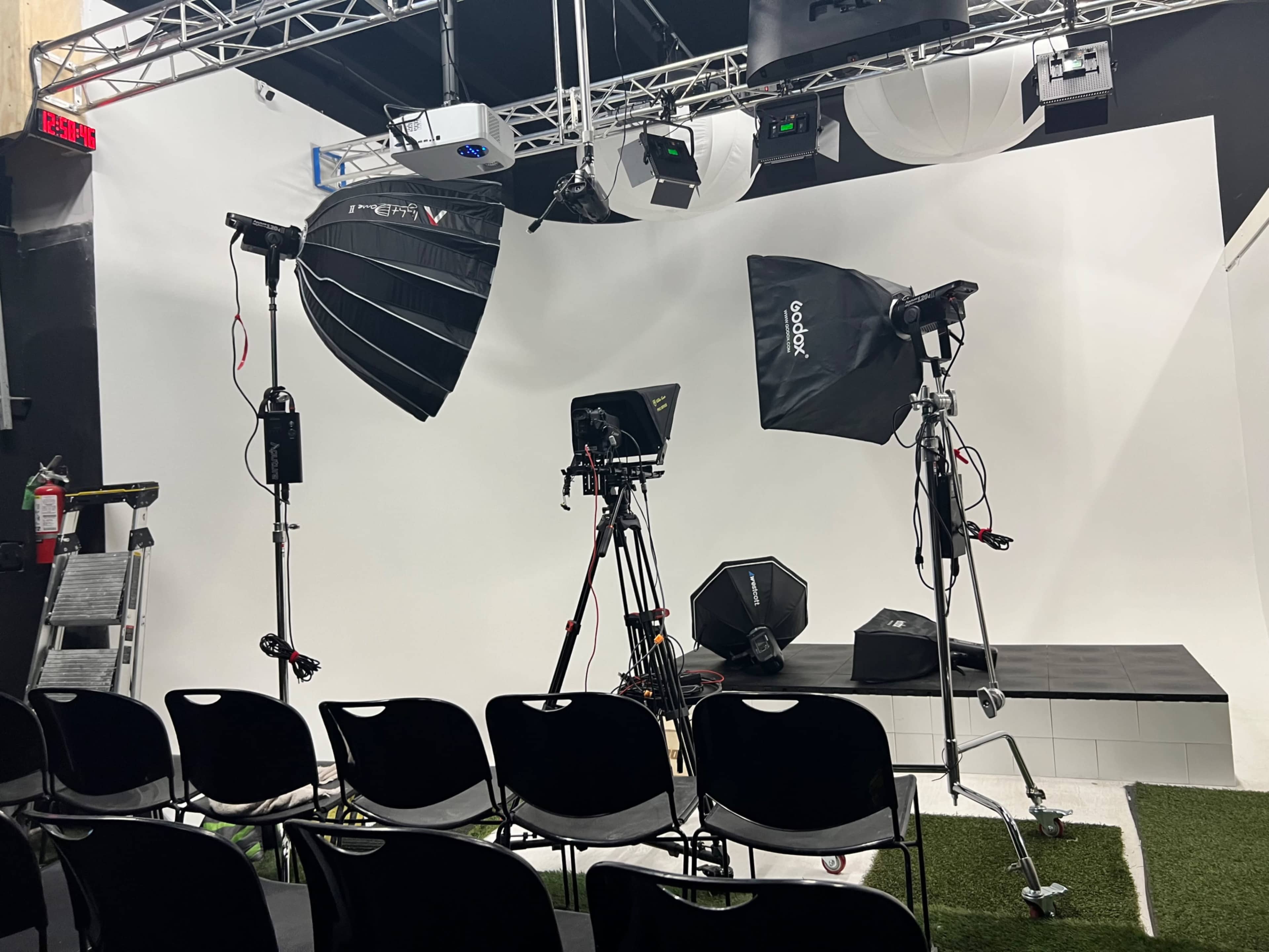 A photography studio setup with various lighting equipment, tripods, and a backdrop.