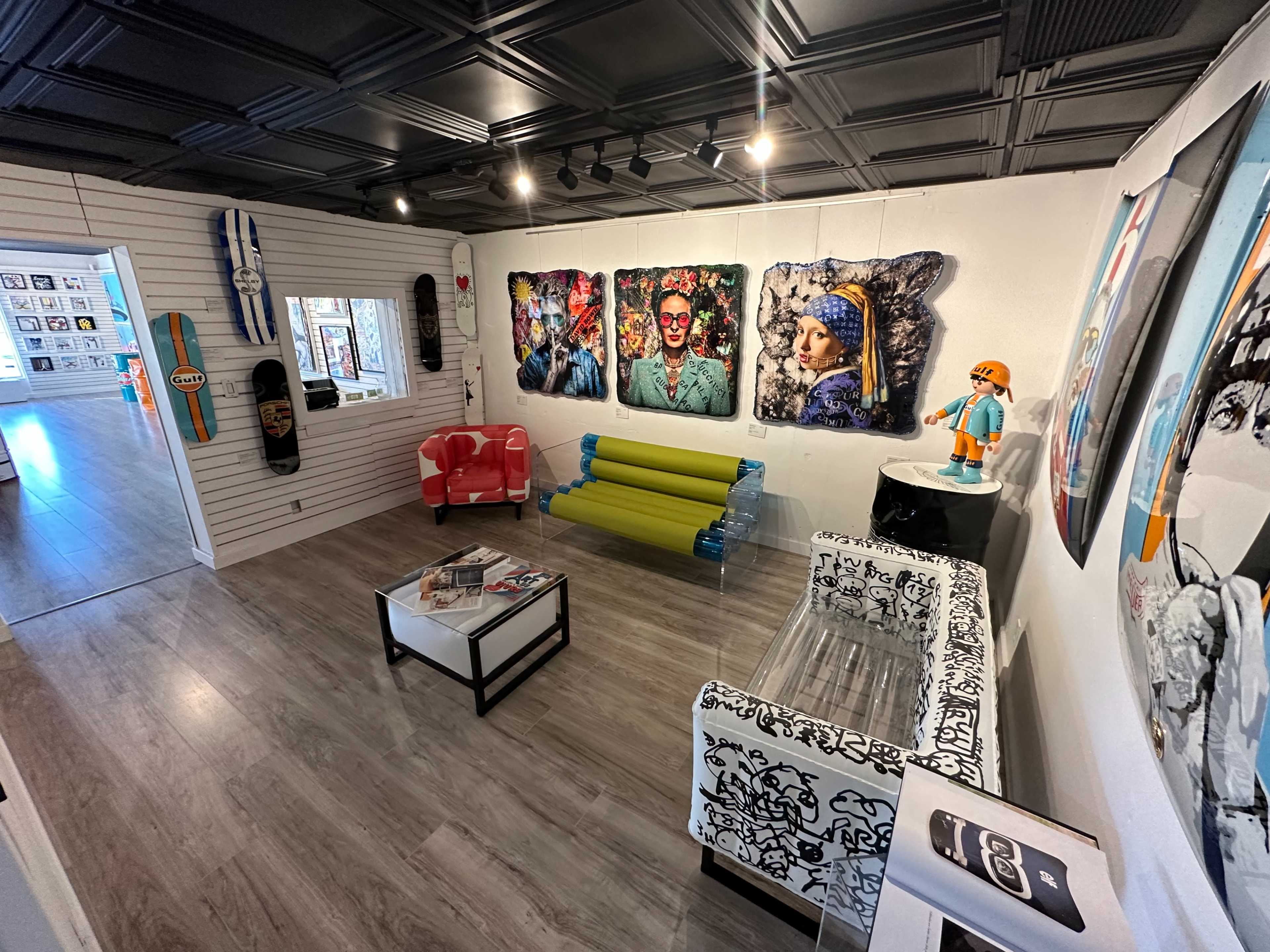 A modern gallery space with various artworks on the walls, colorful seating arrangements, and decorative items.