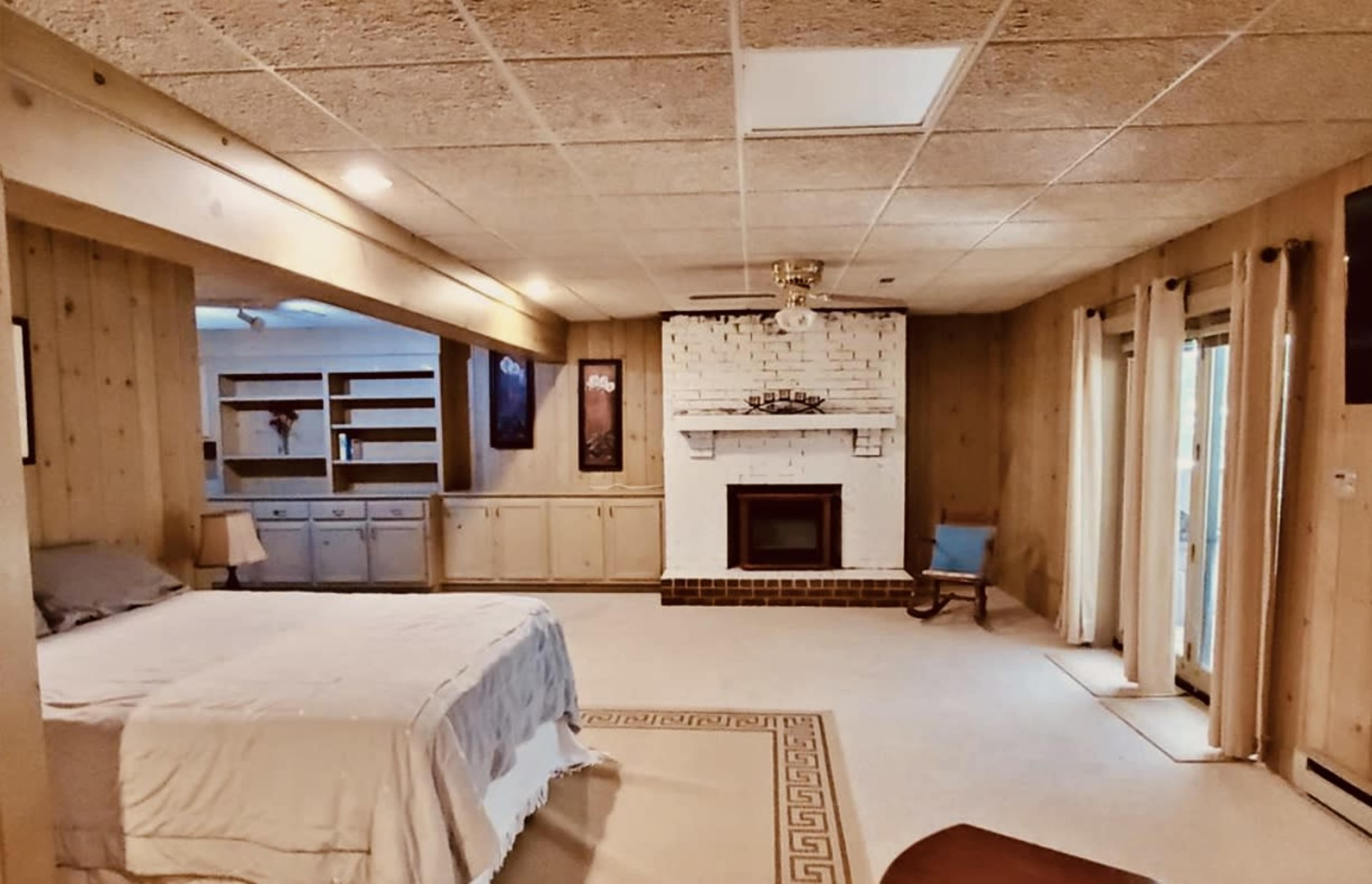 A spacious, well-lit room with a bed, a fireplace, and sliding glass doors leading to an outdoor area.