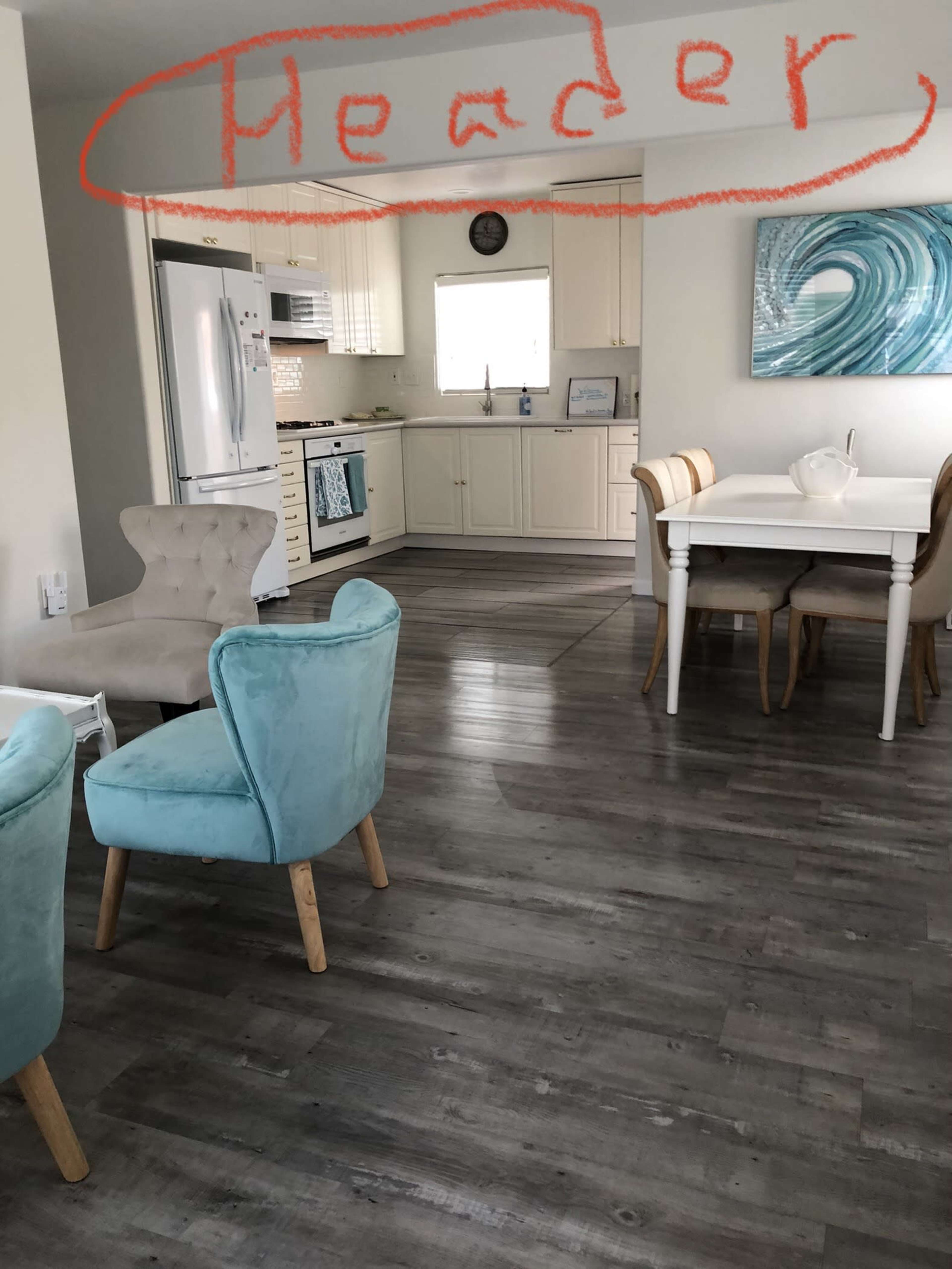 A modern kitchen and dining area feature light-colored cabinetry, a dining table with chairs, and turquoise accent chairs.