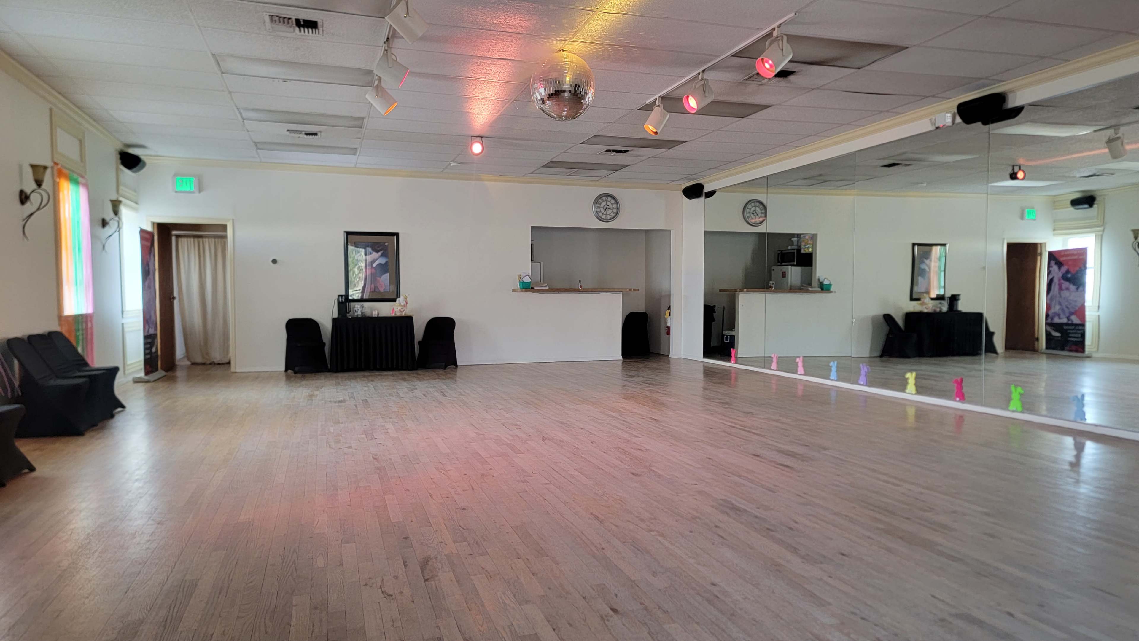 The image shows a spacious dance studio with wooden flooring, mirrored walls, and colorful lights illuminating the area.