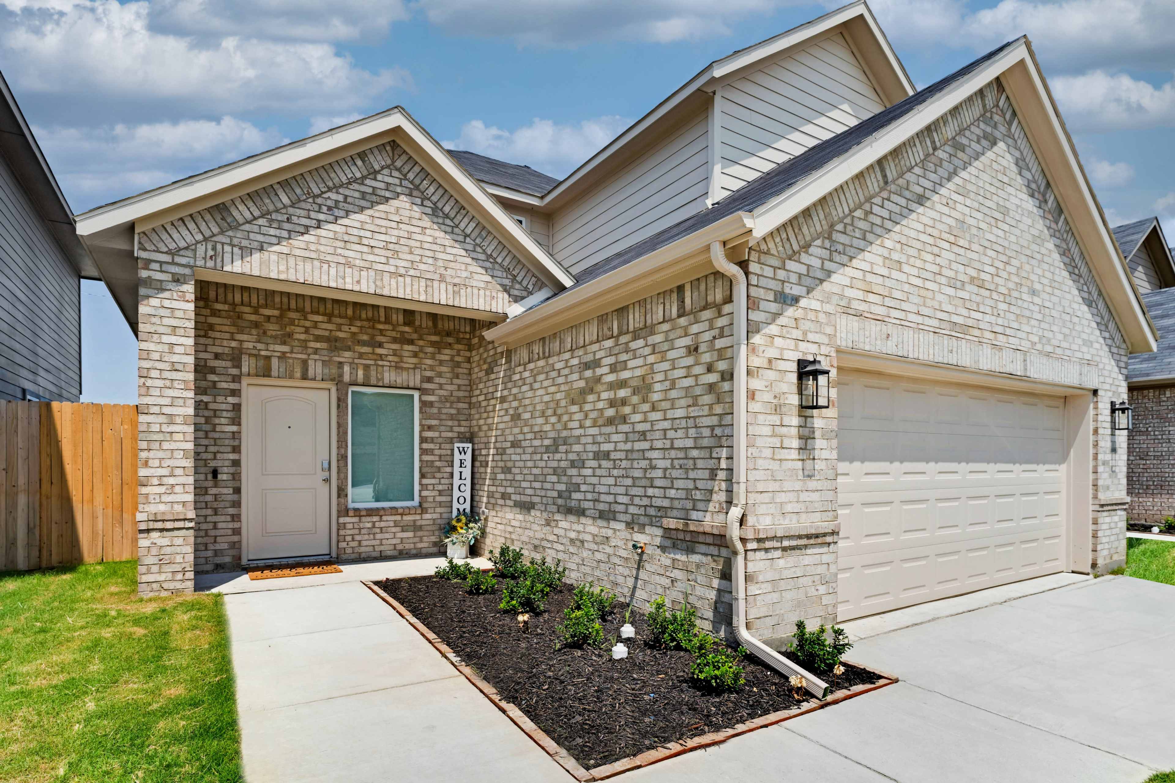 A modern single-story brick house with a landscaped front yard and a two-car garage.