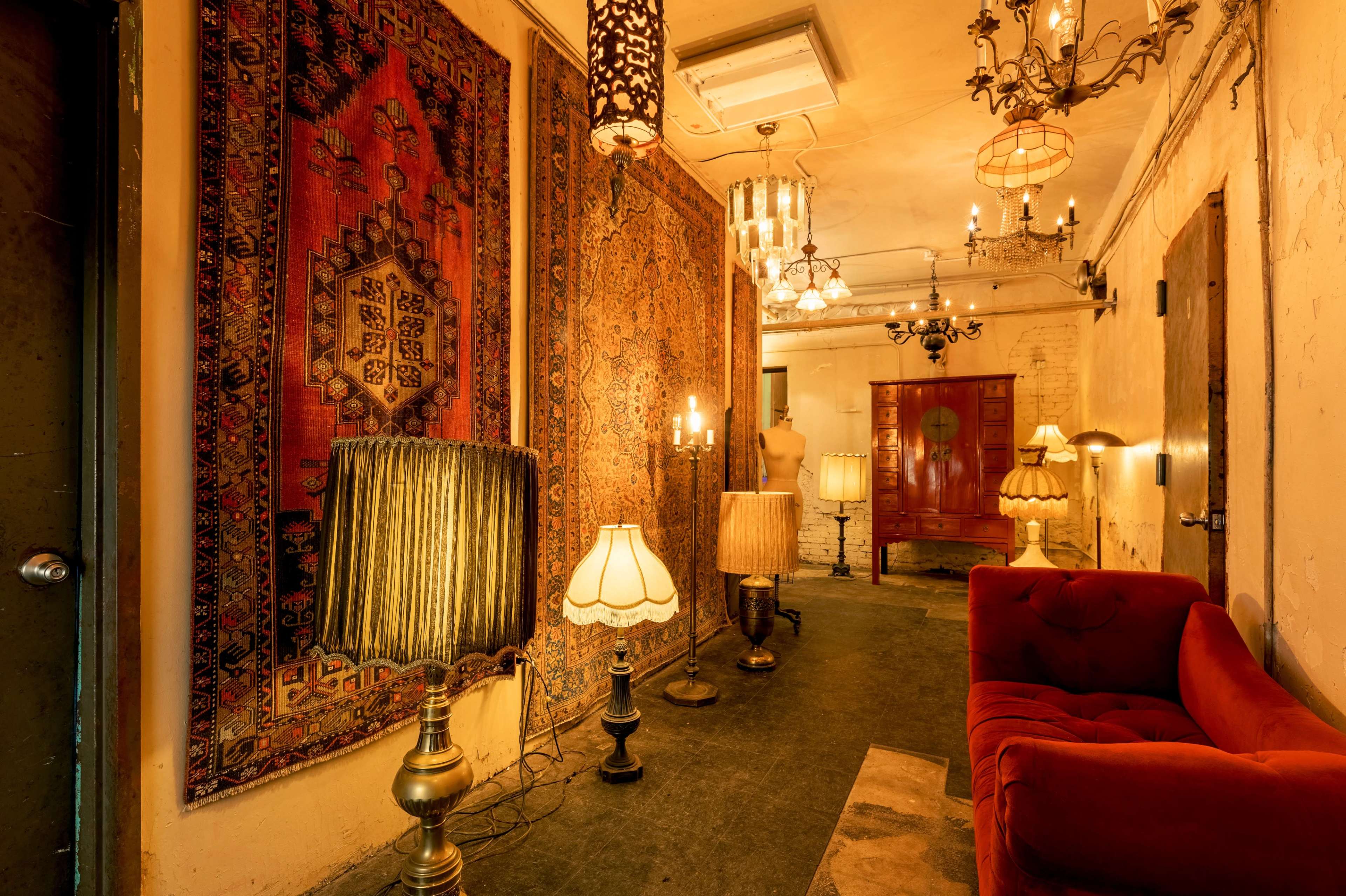 A hallway adorned with vintage rugs, decorative lamps, and a red velvet sofa.