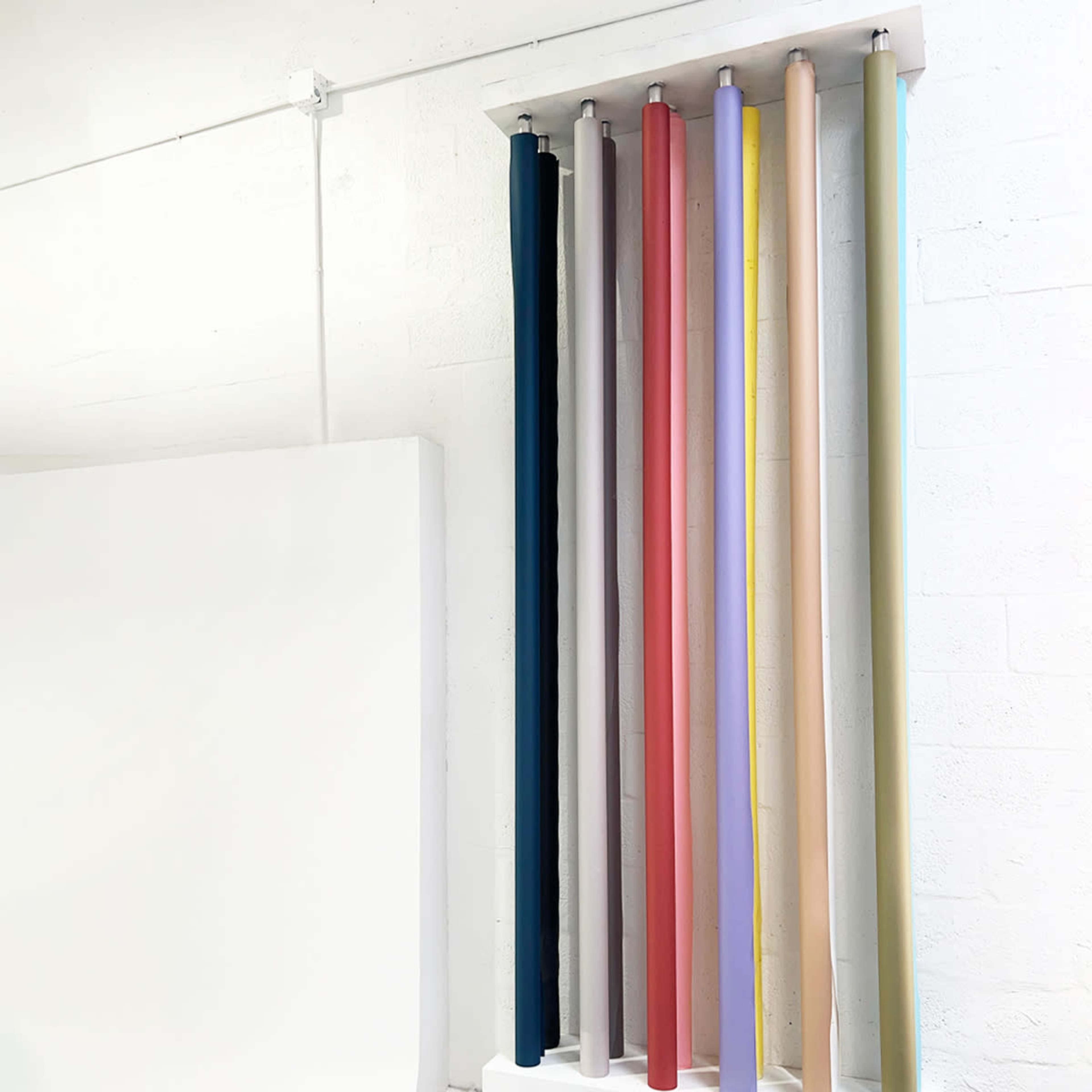A wall-mounted rack displays several rolls of colored fabric in varying shades.