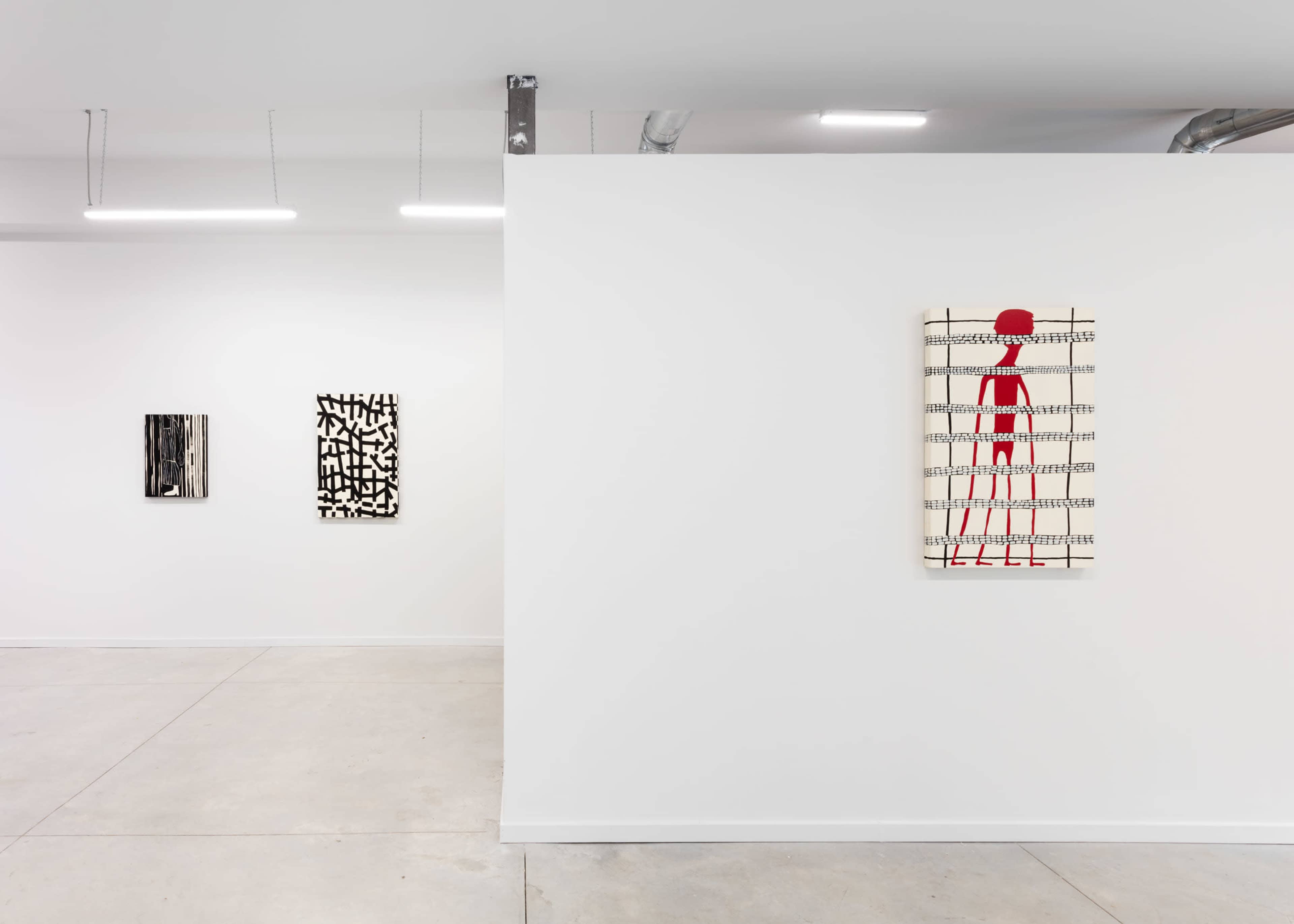 An art gallery interior with three abstract artworks hanging on white walls and concrete flooring.