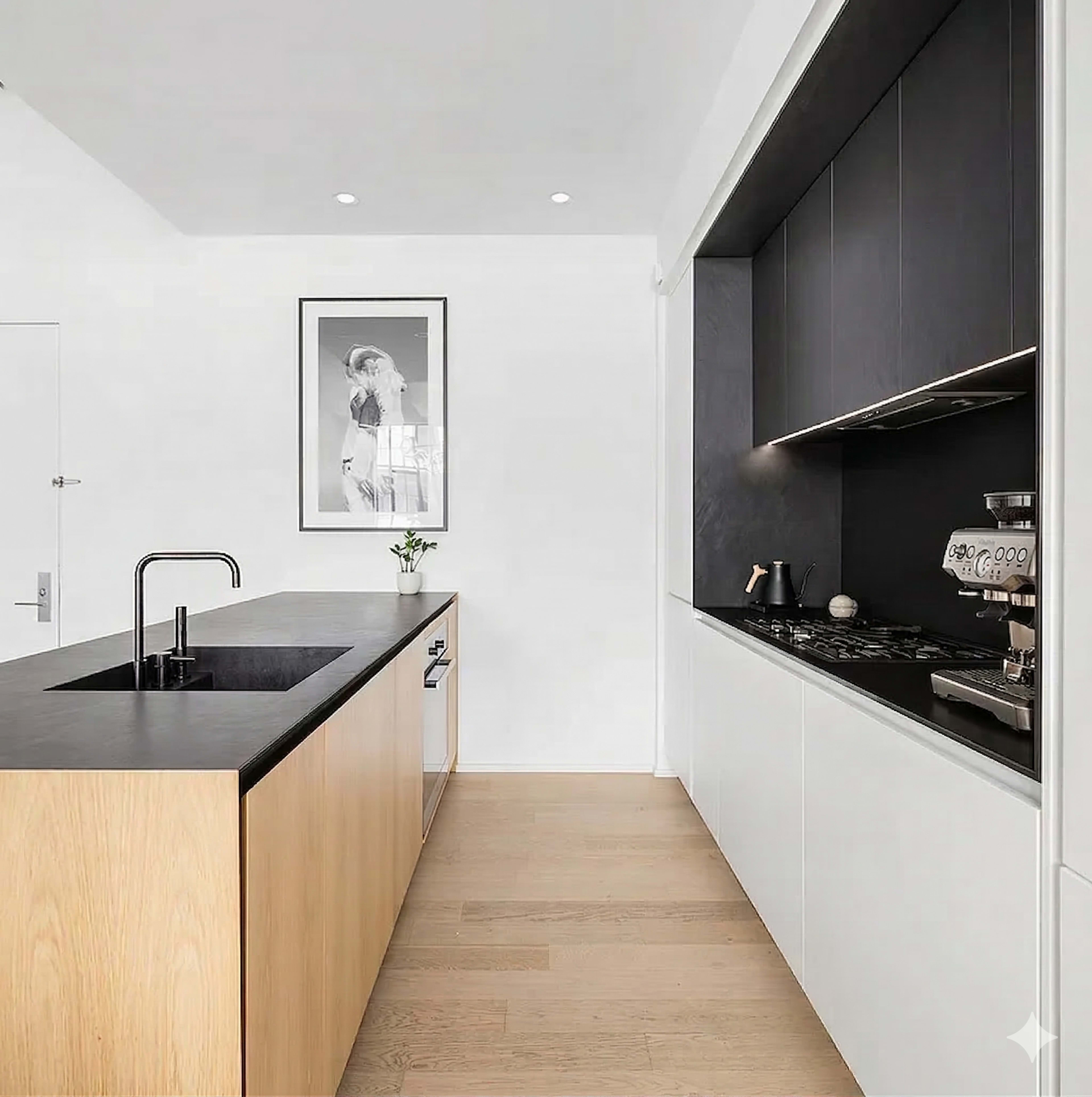 The image shows a modern kitchen with a central island featuring a black countertop, contrasting wooden cabinetry, and sleek black and white cabinetry along one wall.
