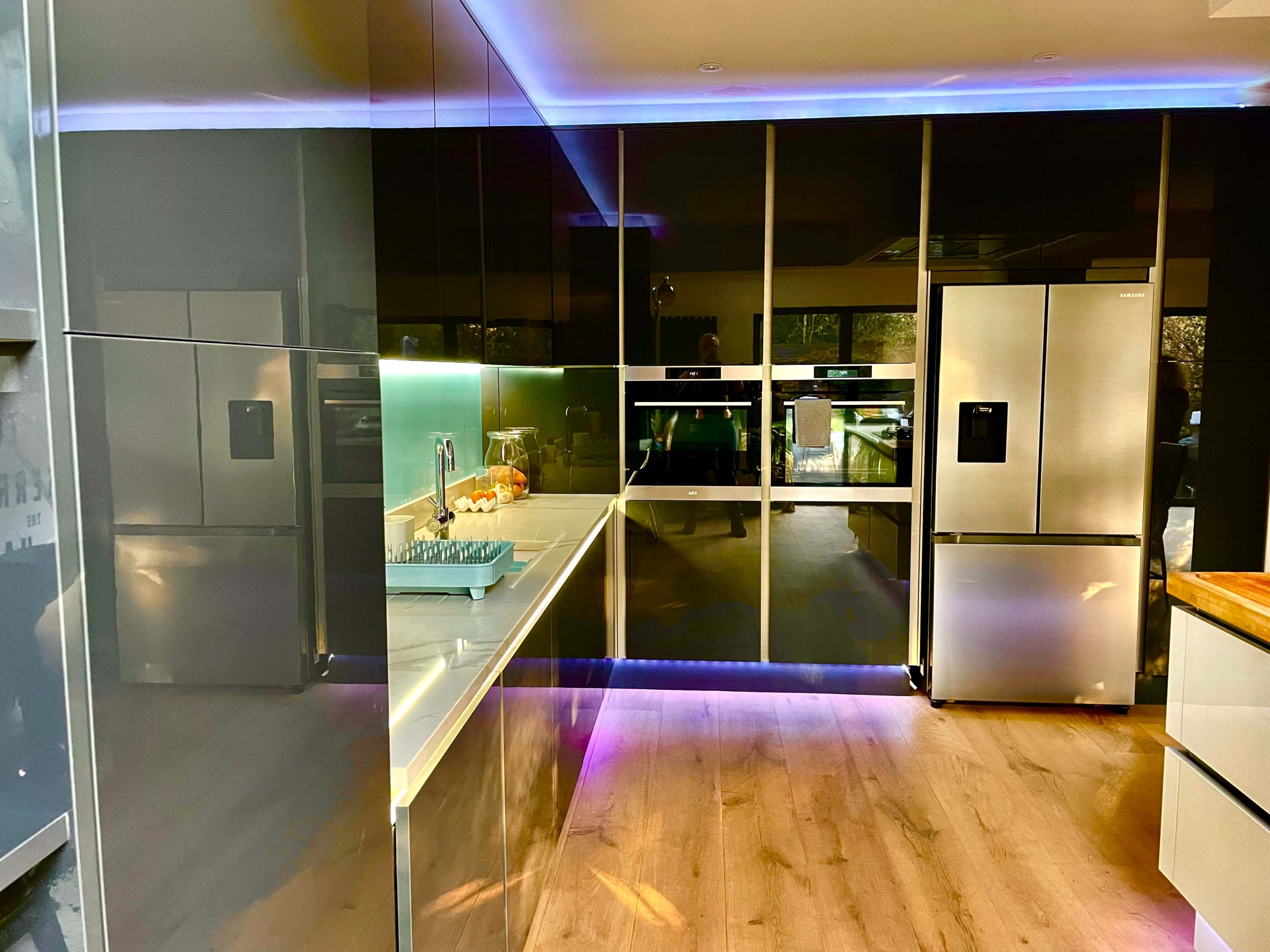 A modern kitchen features sleek cabinets, stainless steel appliances, and LED lighting along the counter.