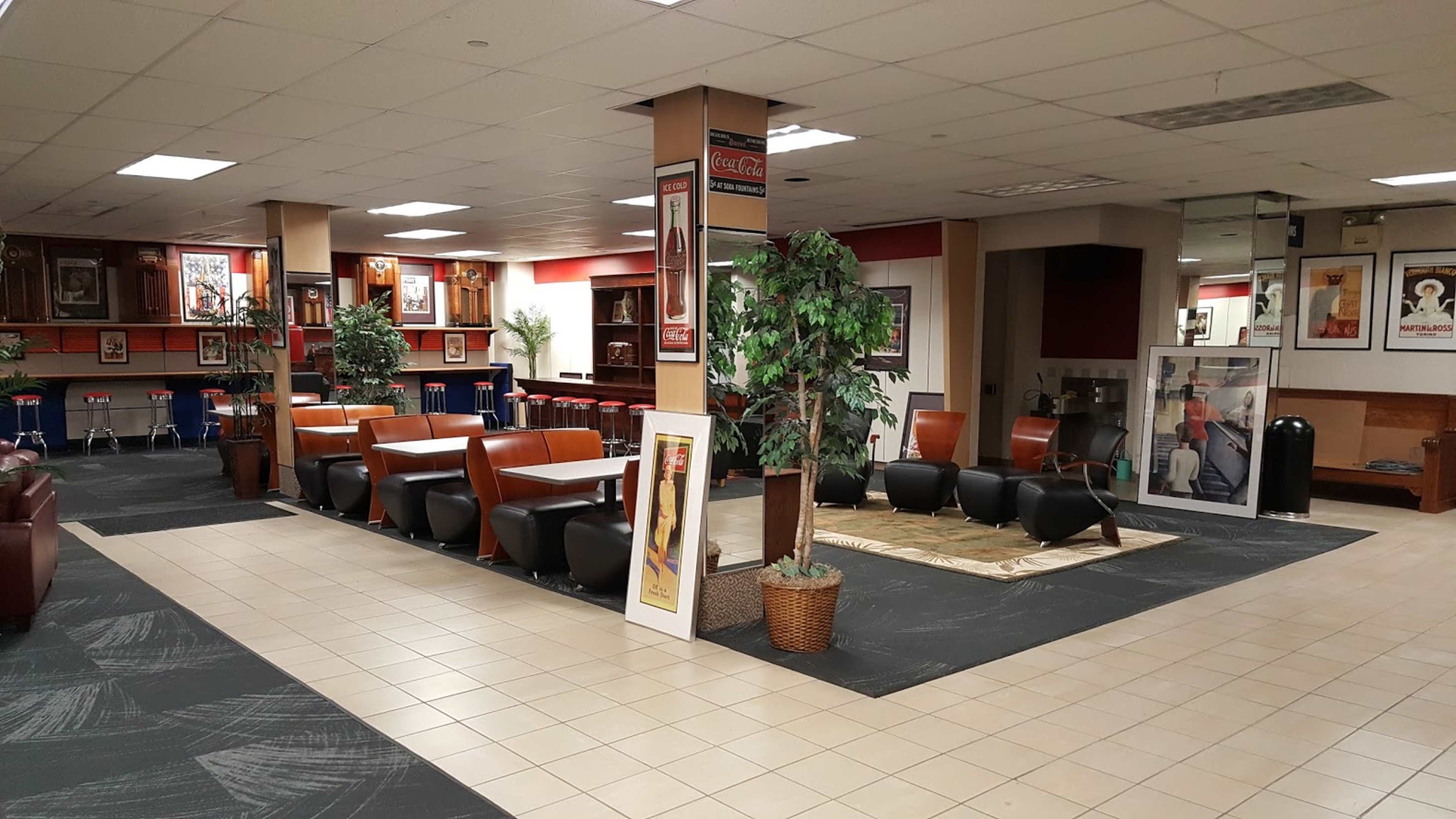 A spacious lounge area with seating arrangements, plants, and artwork displayed along the walls.