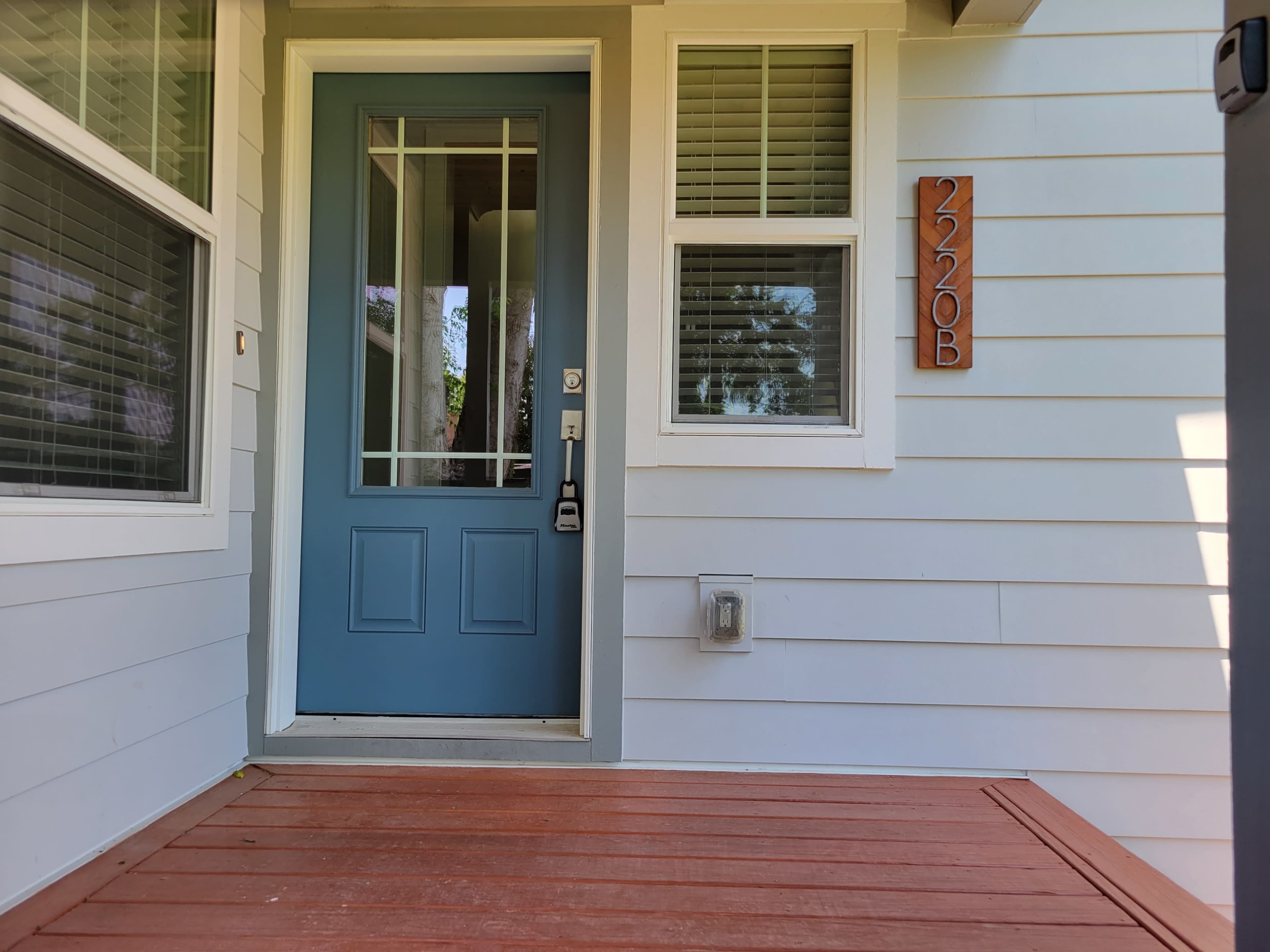 The image shows a front entrance with a blue door and the house number 2220B displayed on the exterior wall.