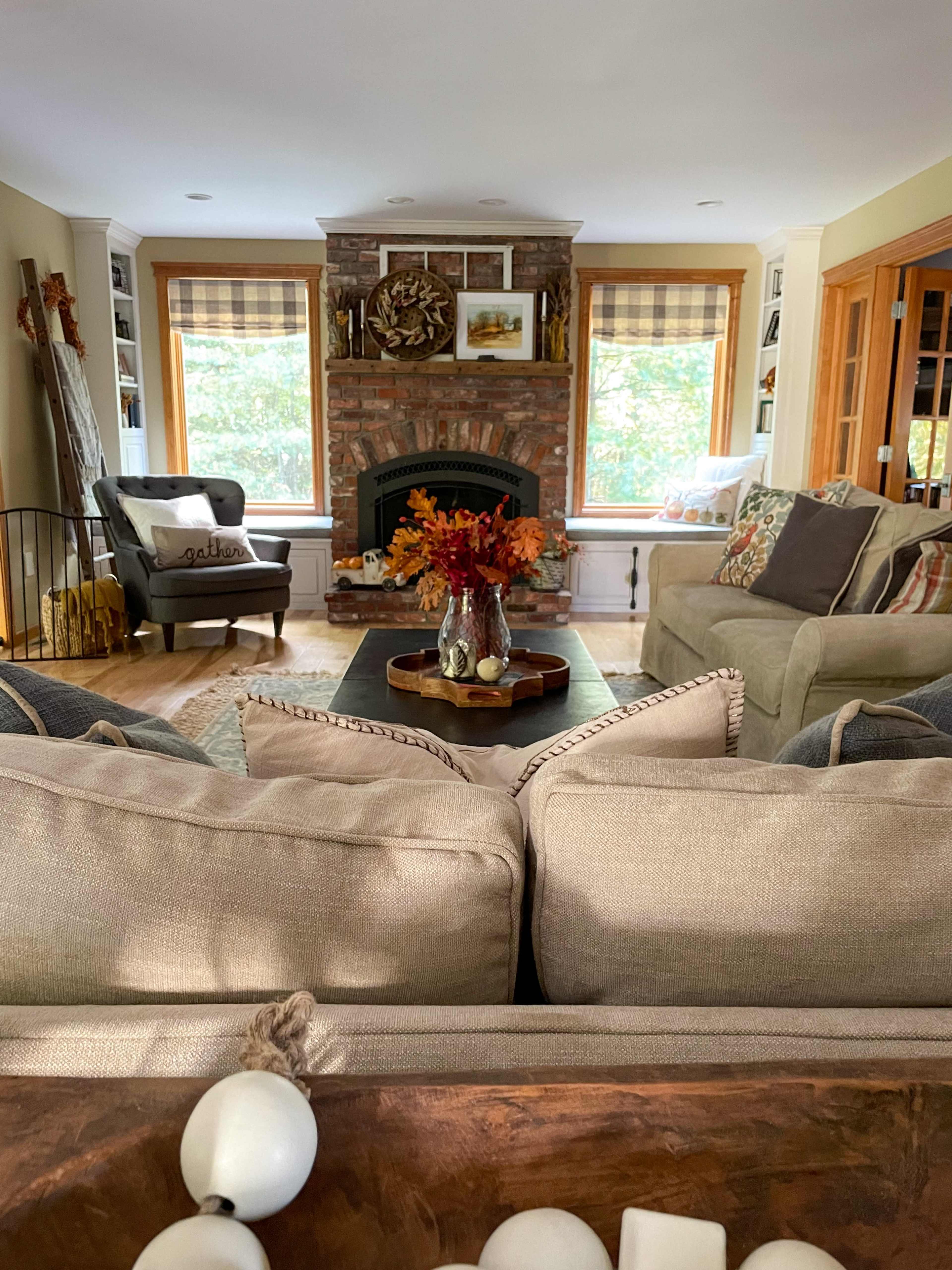 A cozy living room featuring a stone fireplace, comfortable seating arrangements, and a coffee table adorned with decorative items and flowers.