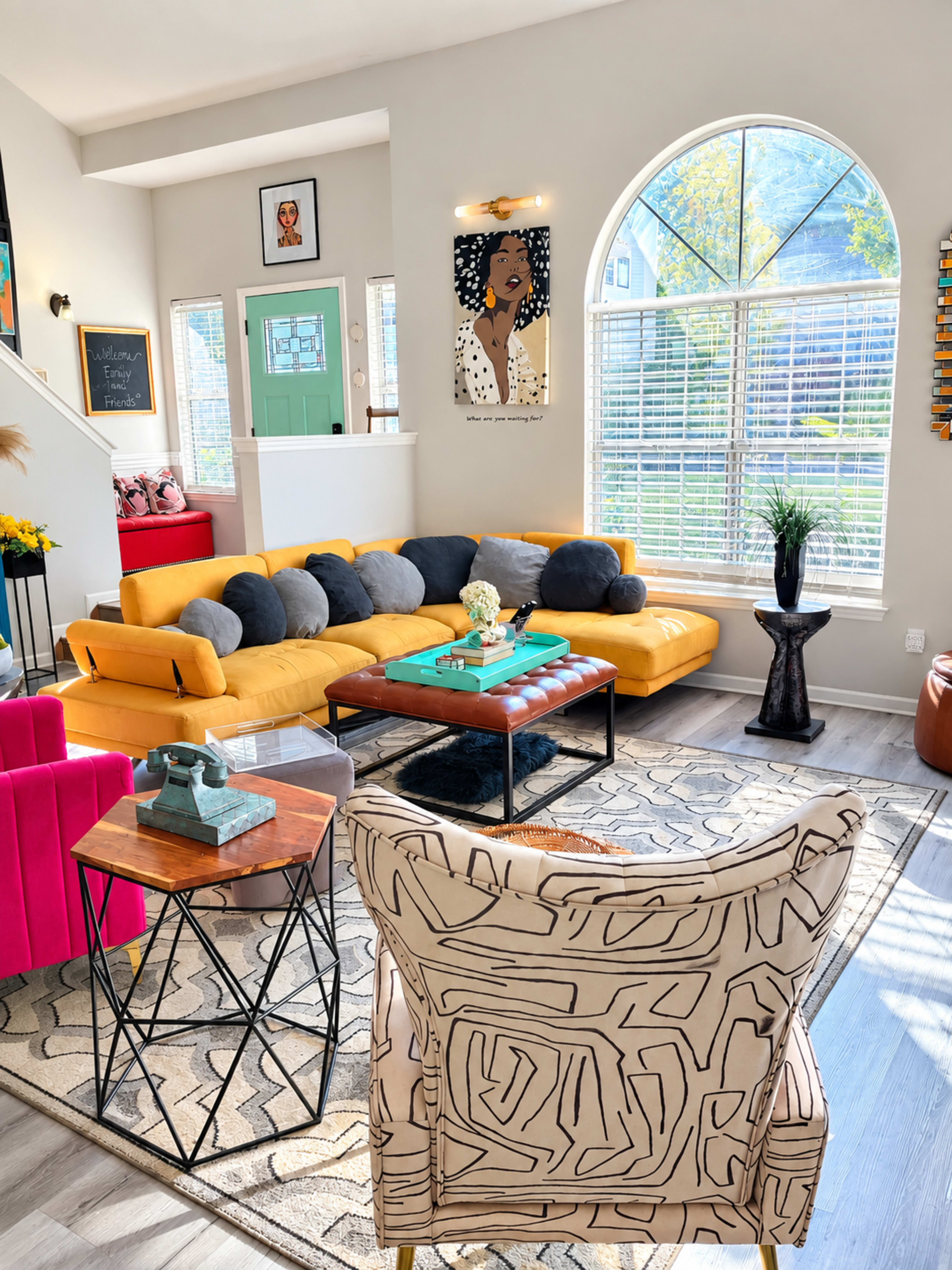 The living room features a yellow sectional sofa, wooden coffee table, and a mix of colorful decor, with large windows allowing natural light to fill the space.