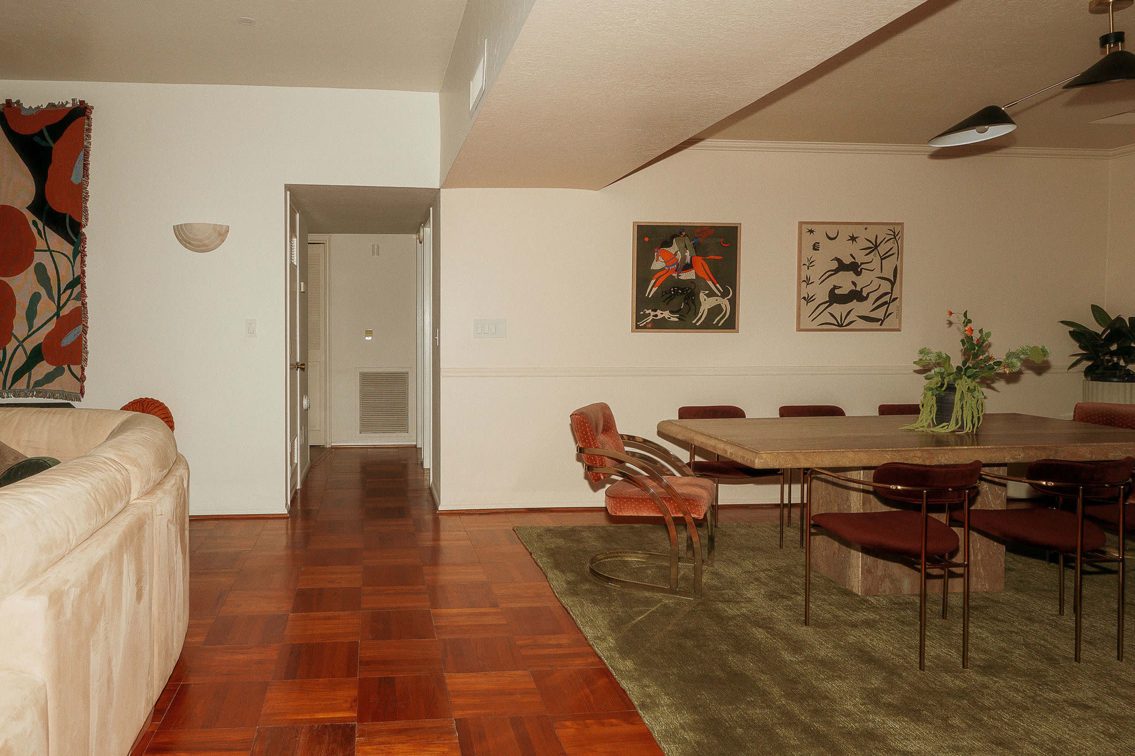 A spacious dining area featuring a large table surrounded by chairs, with a hallway and a door leading to another room in the background.