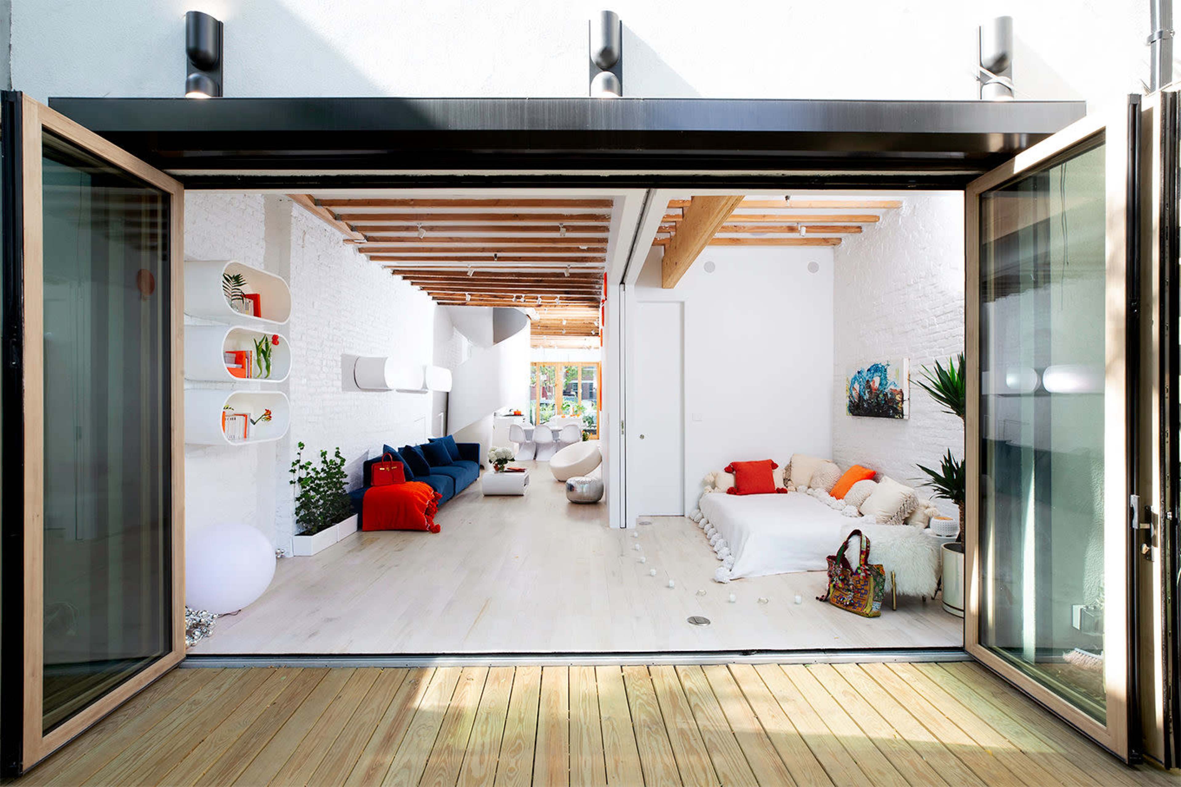 An open-concept modern living space with large folding glass doors leading to a wooden deck.