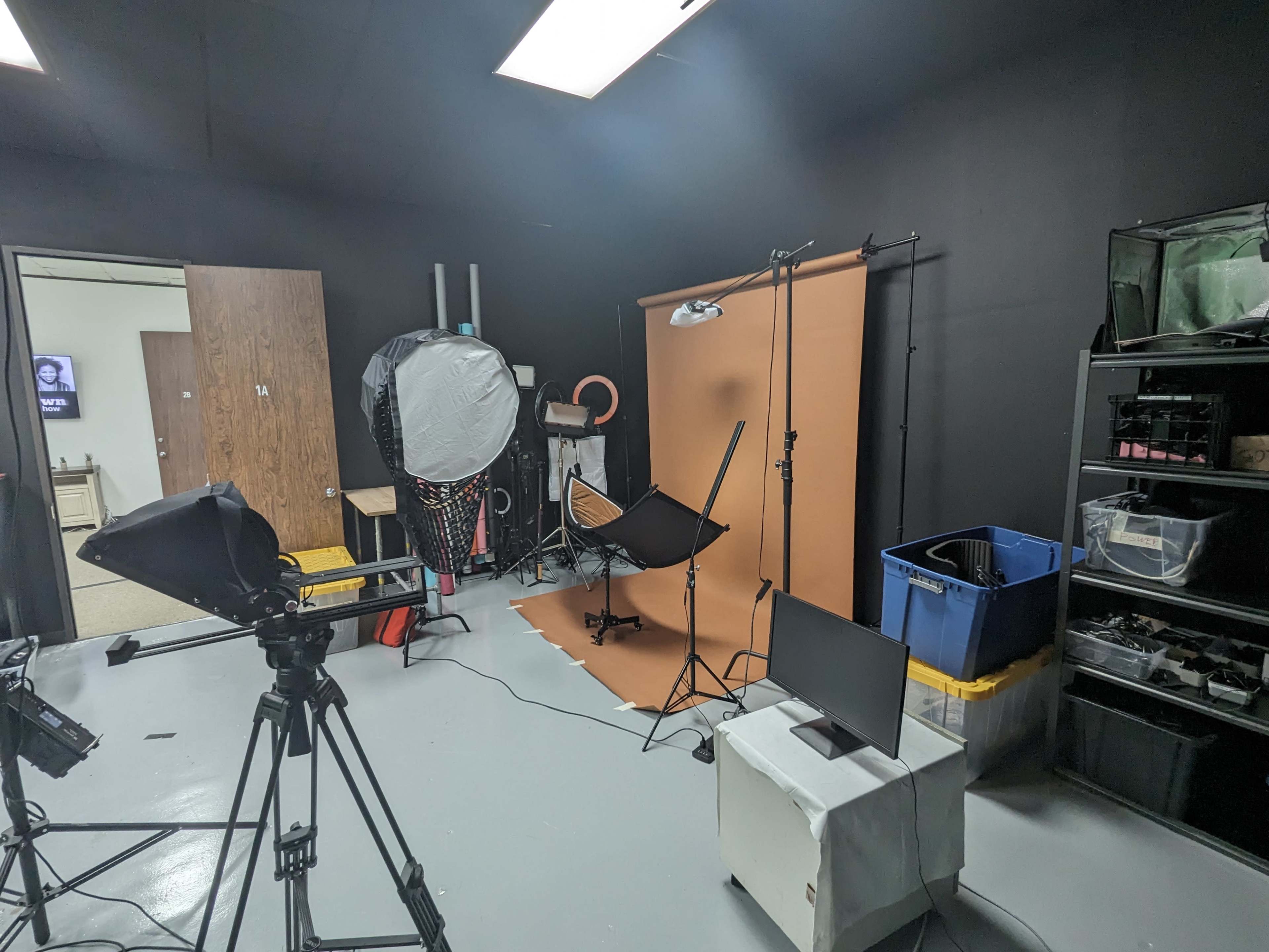 A photography studio setup with a backdrop, lighting equipment, and various props organized on shelves.