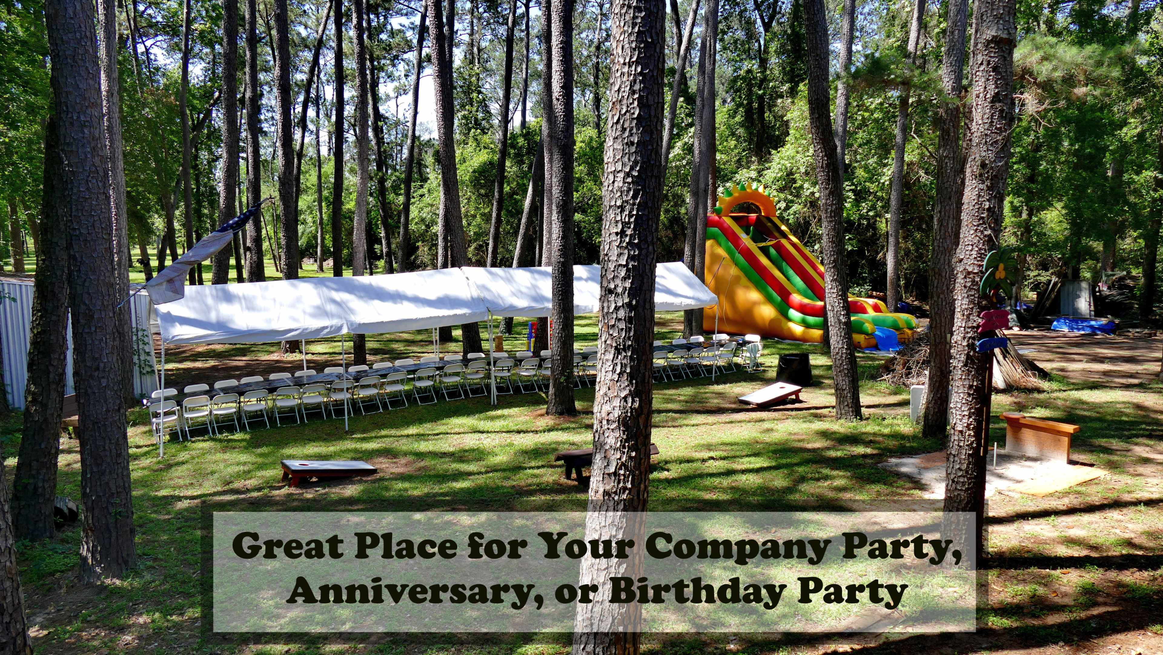 A tent with rows of chairs is set up in a wooded area alongside a colorful inflatable slide.
