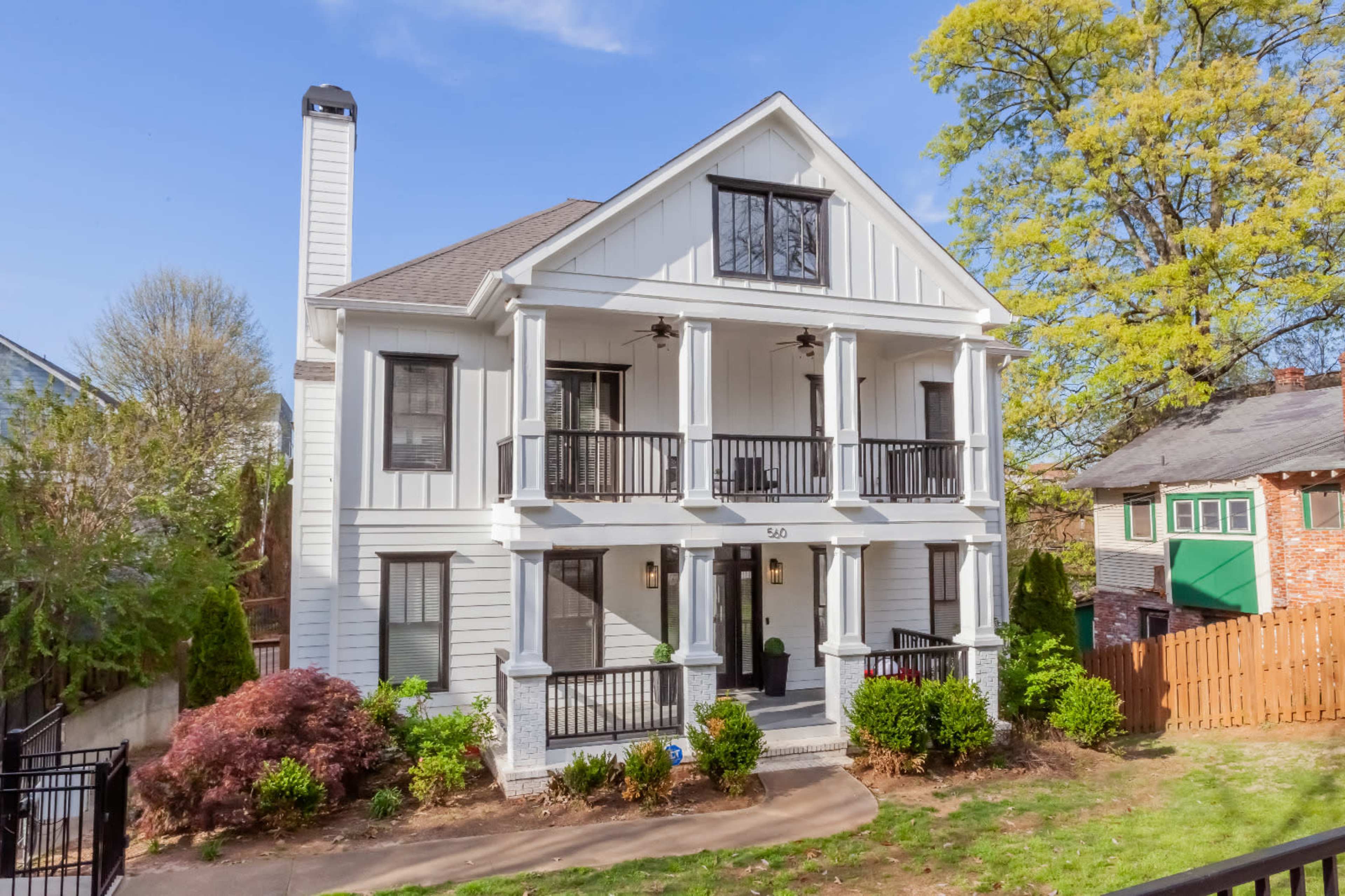 A two-story house with a symmetrical design, featuring a front porch with four columns and a landscaped yard.