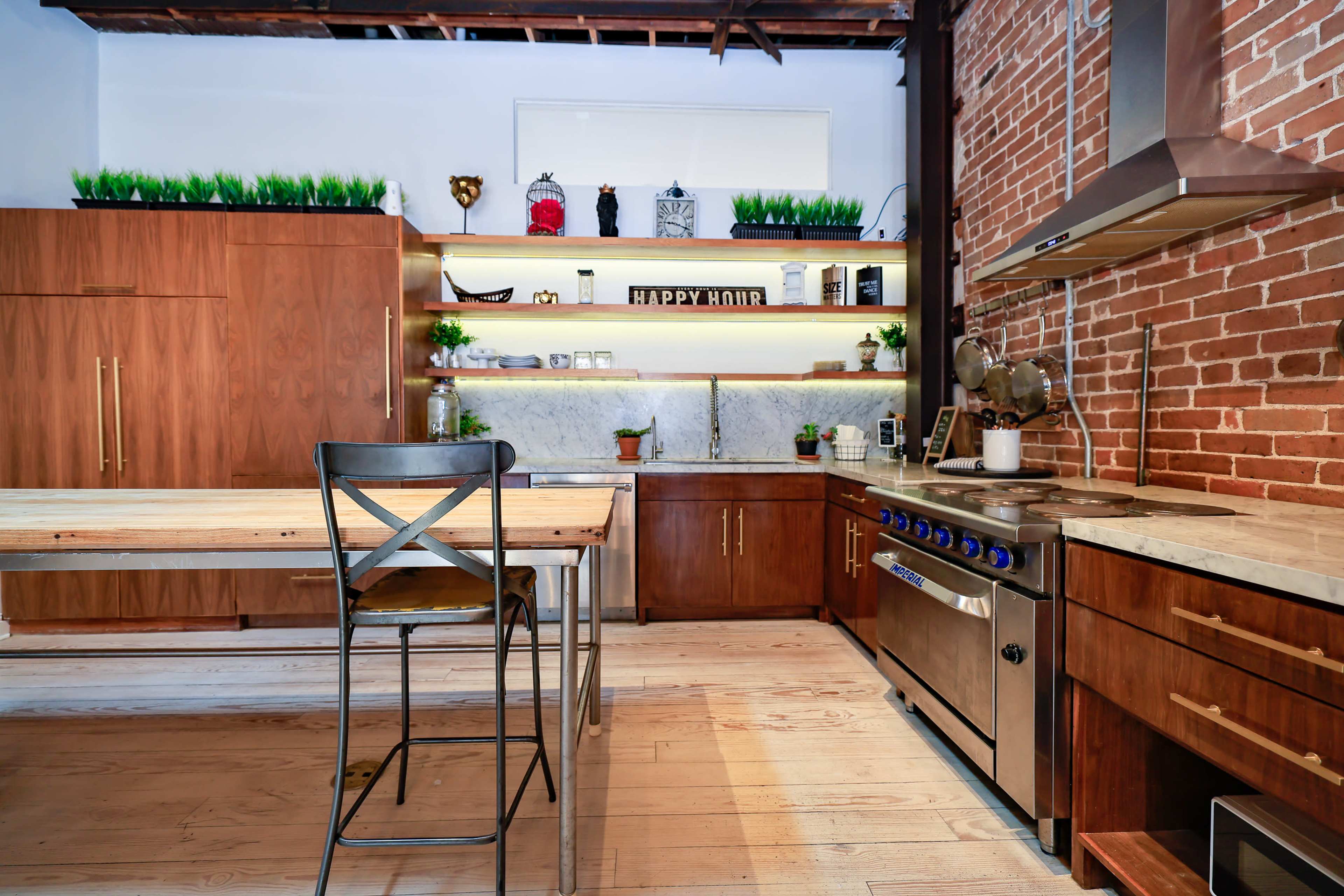 The kitchen features wood cabinetry, metal appliances, and a central wooden table with an industrial-style chair.