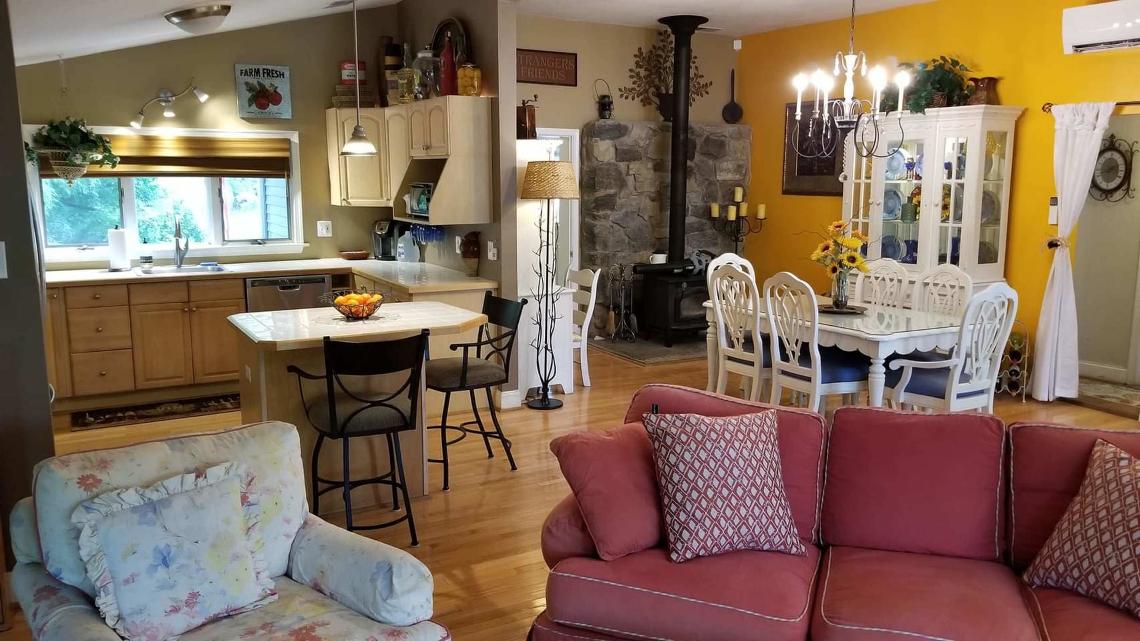 The image shows a cozy open-concept living space featuring a kitchen with wooden cabinets and an adjacent dining area with a table and chairs, as well as a comfortable seating arrangement in the living room.