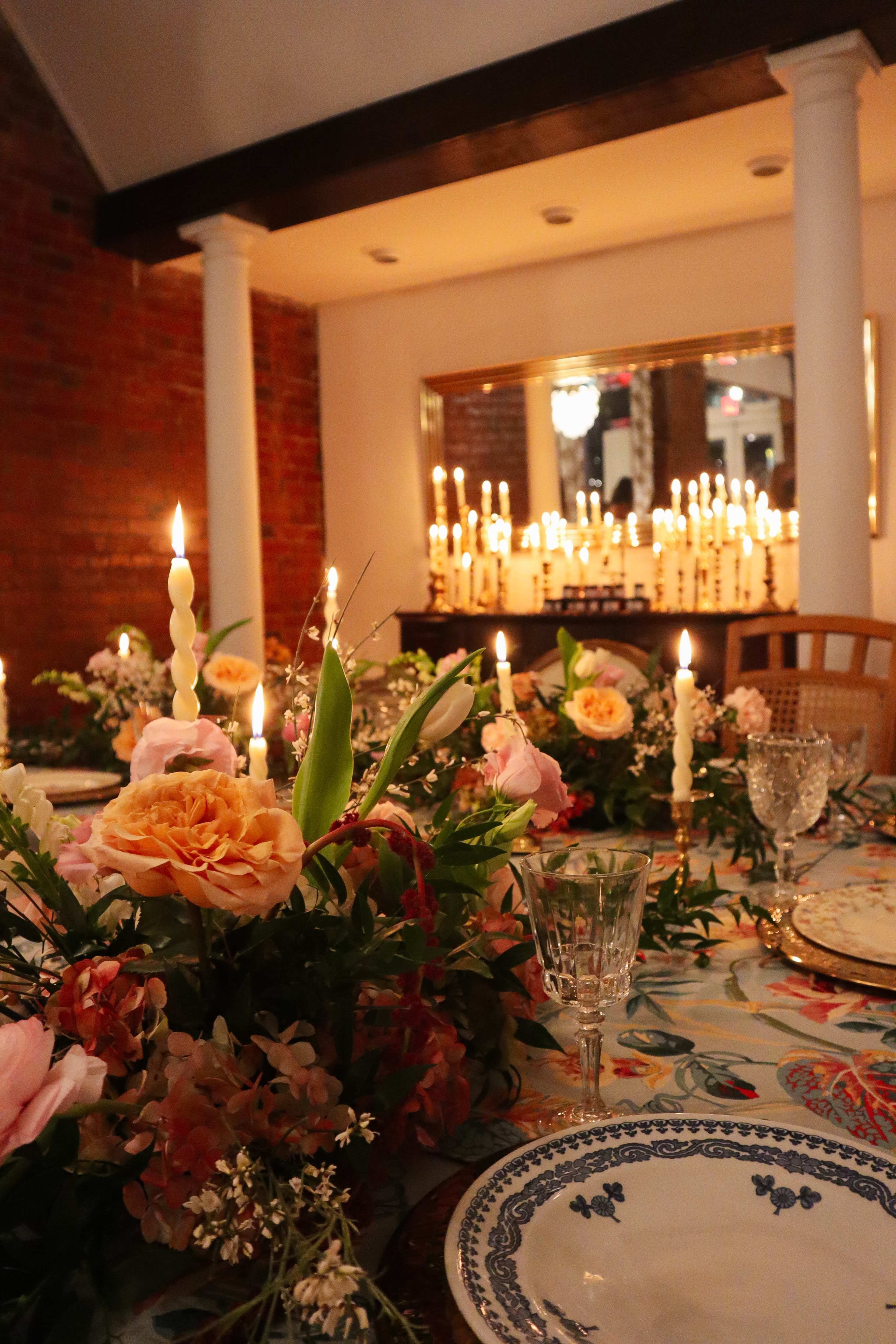 A beautifully arranged dining table is adorned with floral centerpieces and illuminated by numerous candles, creating a warm, inviting atmosphere.
